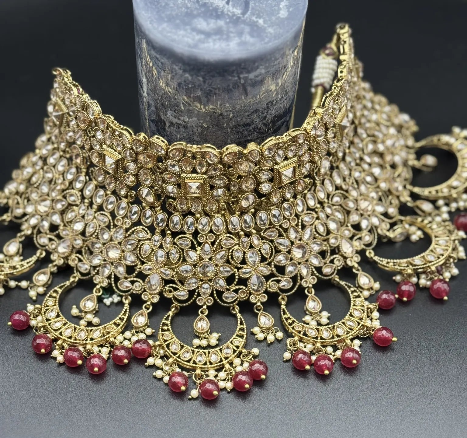 choker focused view exquisite gold-plated Indian bridal set with red accents, sparkling stones & matching earrings, teeka and a long traditional necklace. Waterproof & anti-tarnish.
