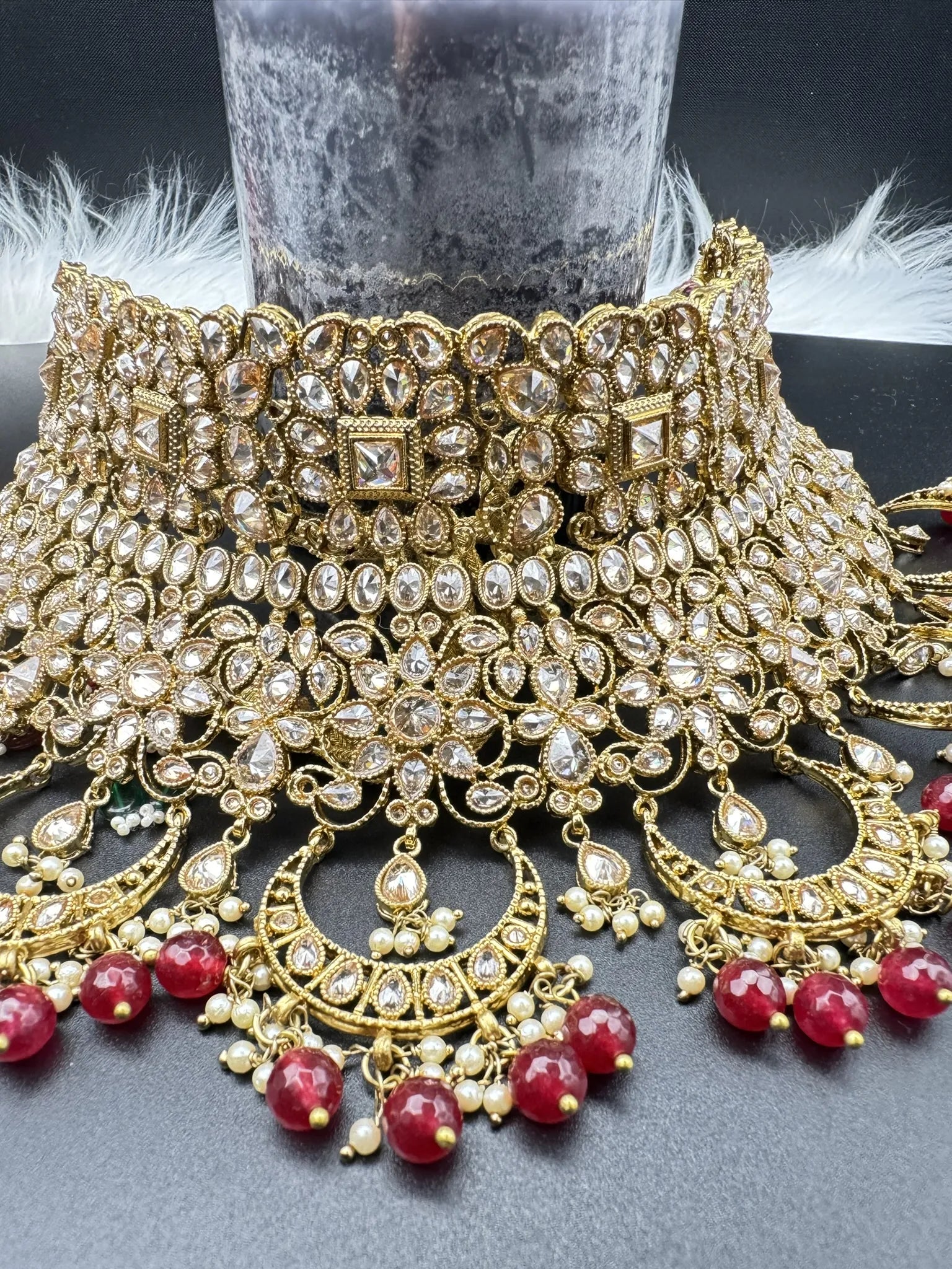 choker focused view exquisite gold-plated Indian bridal set with red accents, sparkling stones & matching earrings, teeka and a long traditional necklace. Waterproof & anti-tarnish.