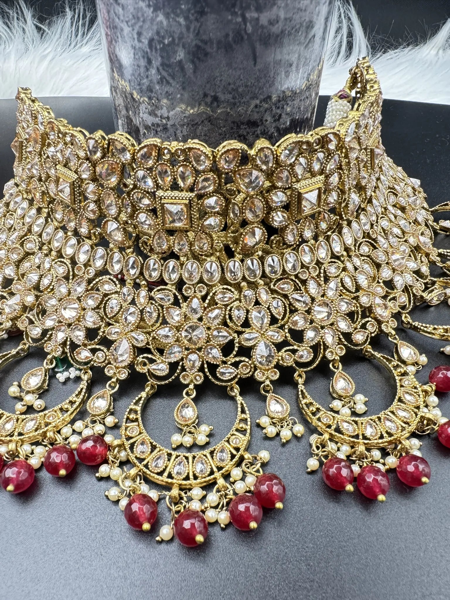 choker focused view exquisite gold-plated Indian bridal set with red accents, sparkling stones & matching earrings, teeka and a long traditional necklace. Waterproof & anti-tarnish.