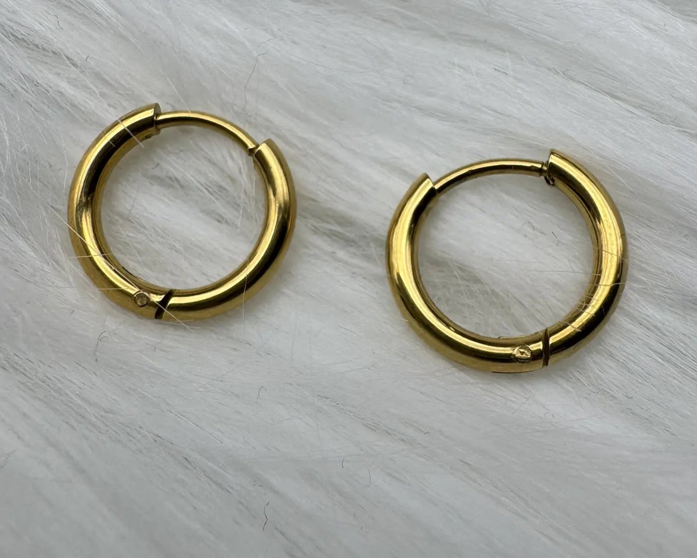 gold plated hoop earring on a furry white cloth 