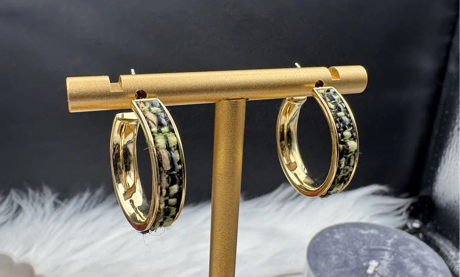gold plated hoop earrings with camouflage style pattern on a stand with a black background