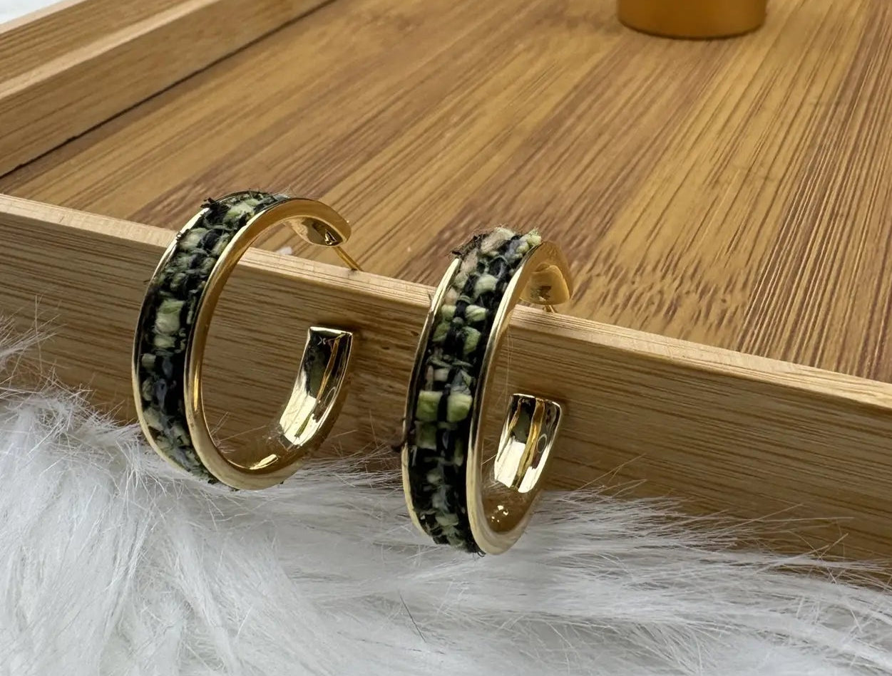 gold plated hoop earrings with camouflage style pattern on a wooden tray