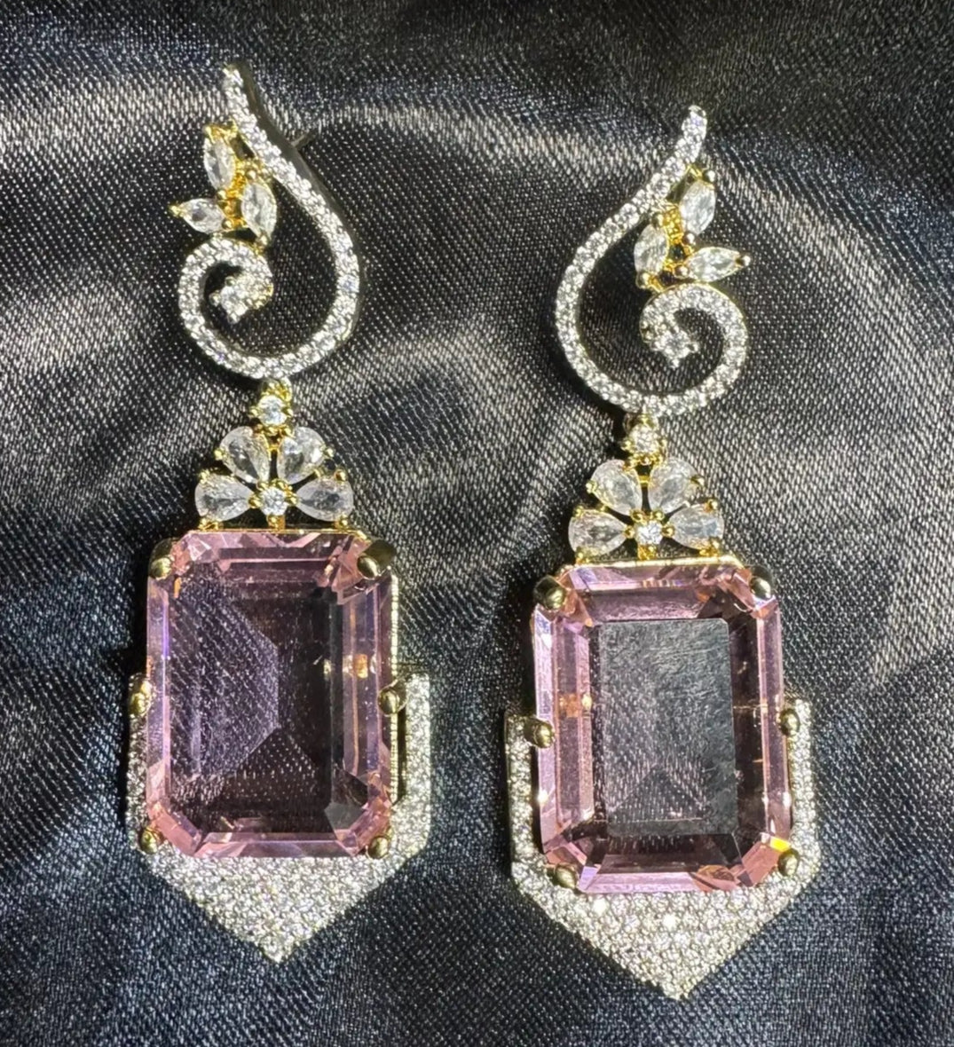 Pair of earrings with pink gemstones on a dark fabric background