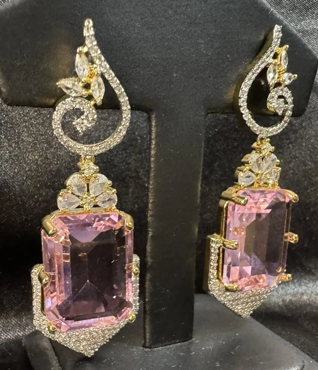 Pair of earrings with pink gemstones on a black stand