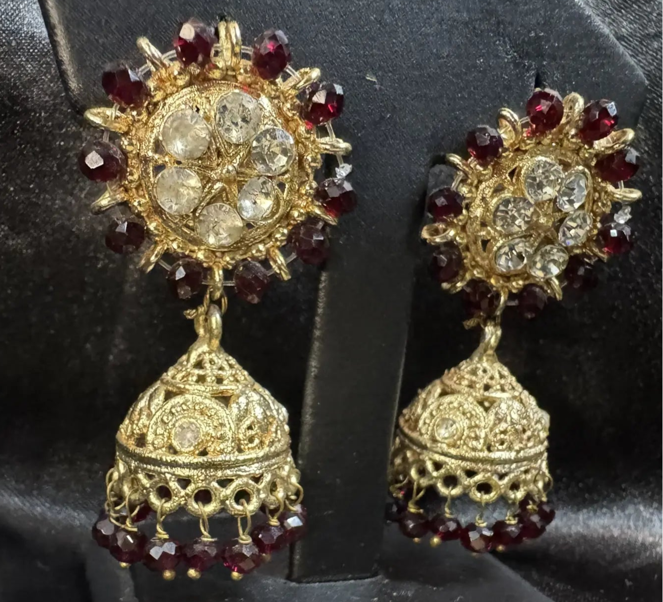 Gold and red gemstone jhumkay earrings on a black stand