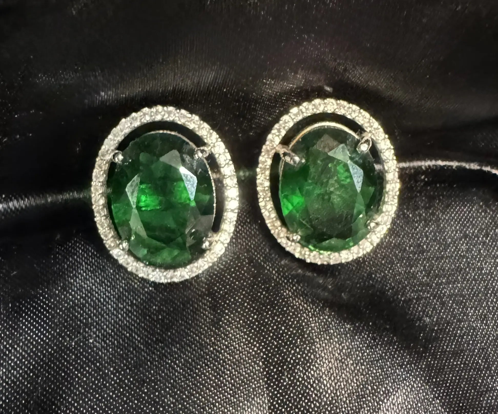 Pair of emerald green gemstone earrings on a black background