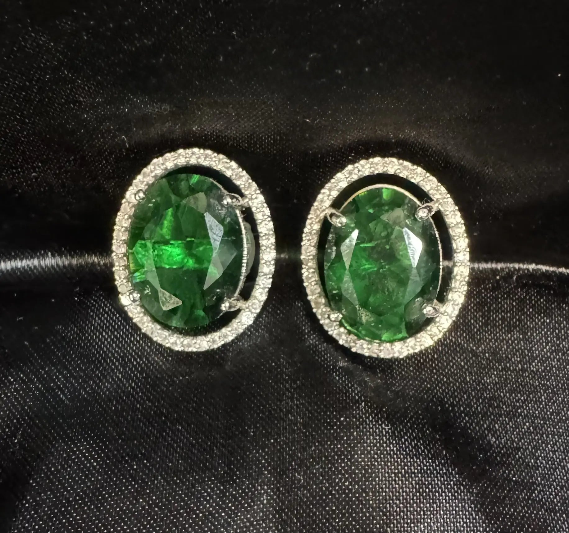 Pair of stud earrings with green gemstones on a black background