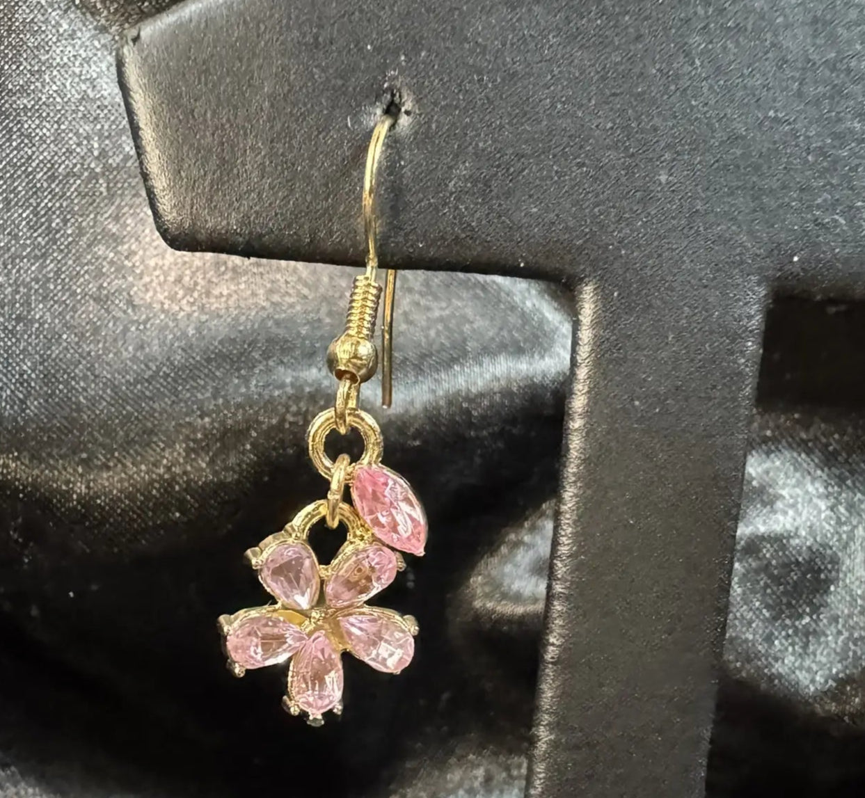 Gold plated earring with pink gemstones on a black stand
