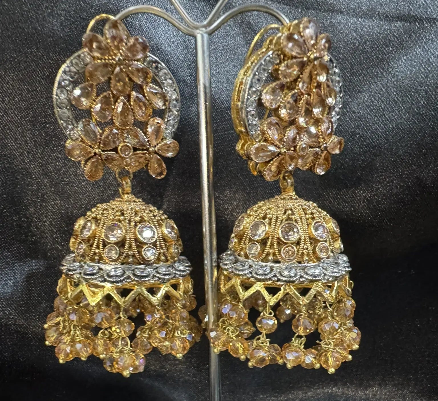 frontal view of Pakistani design gold-plated jhumkay with champagne colored gemstones and floral accents