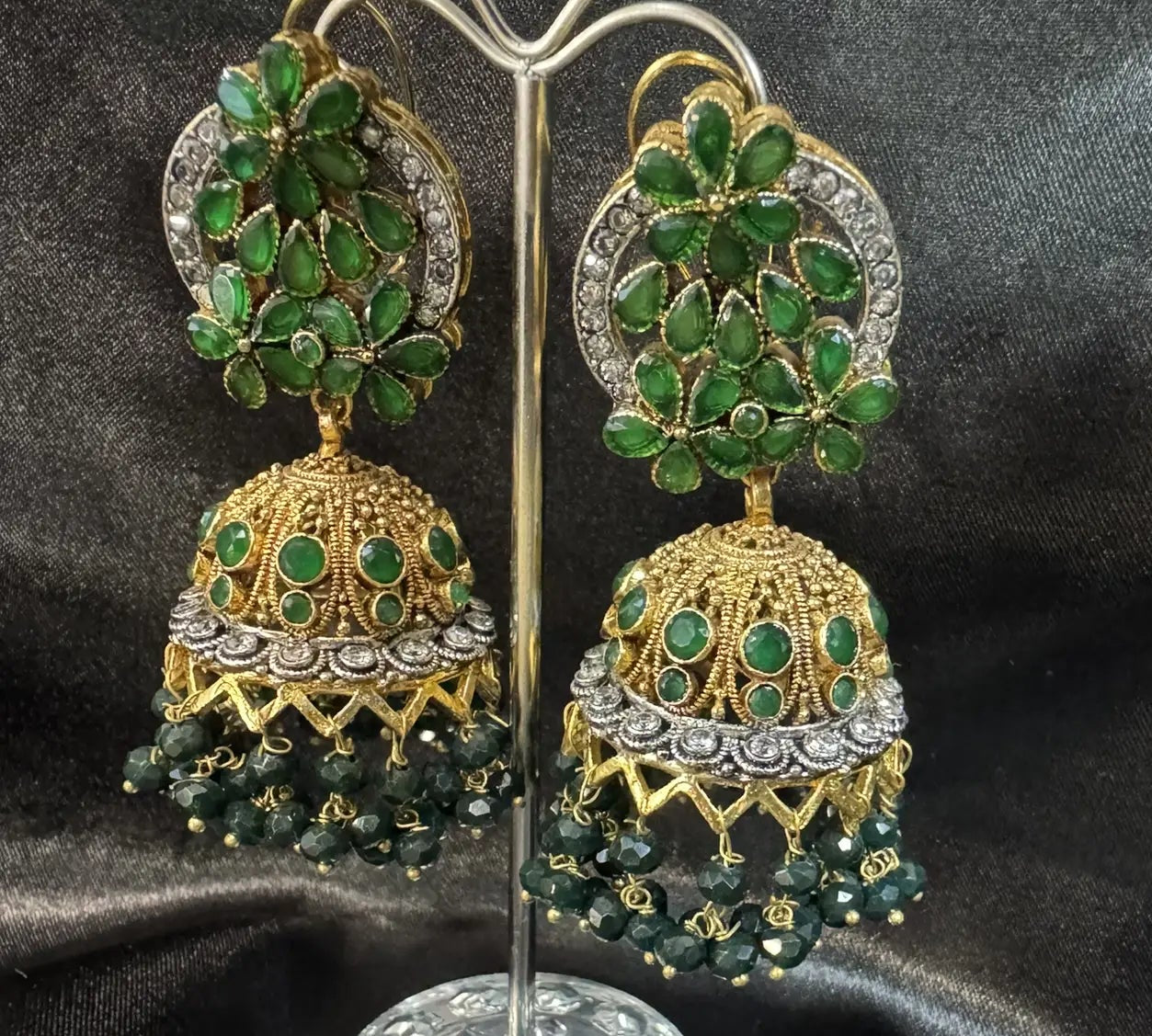right side view of Pakistani design gold-plated jhumkay with green colored gemstones and floral accents