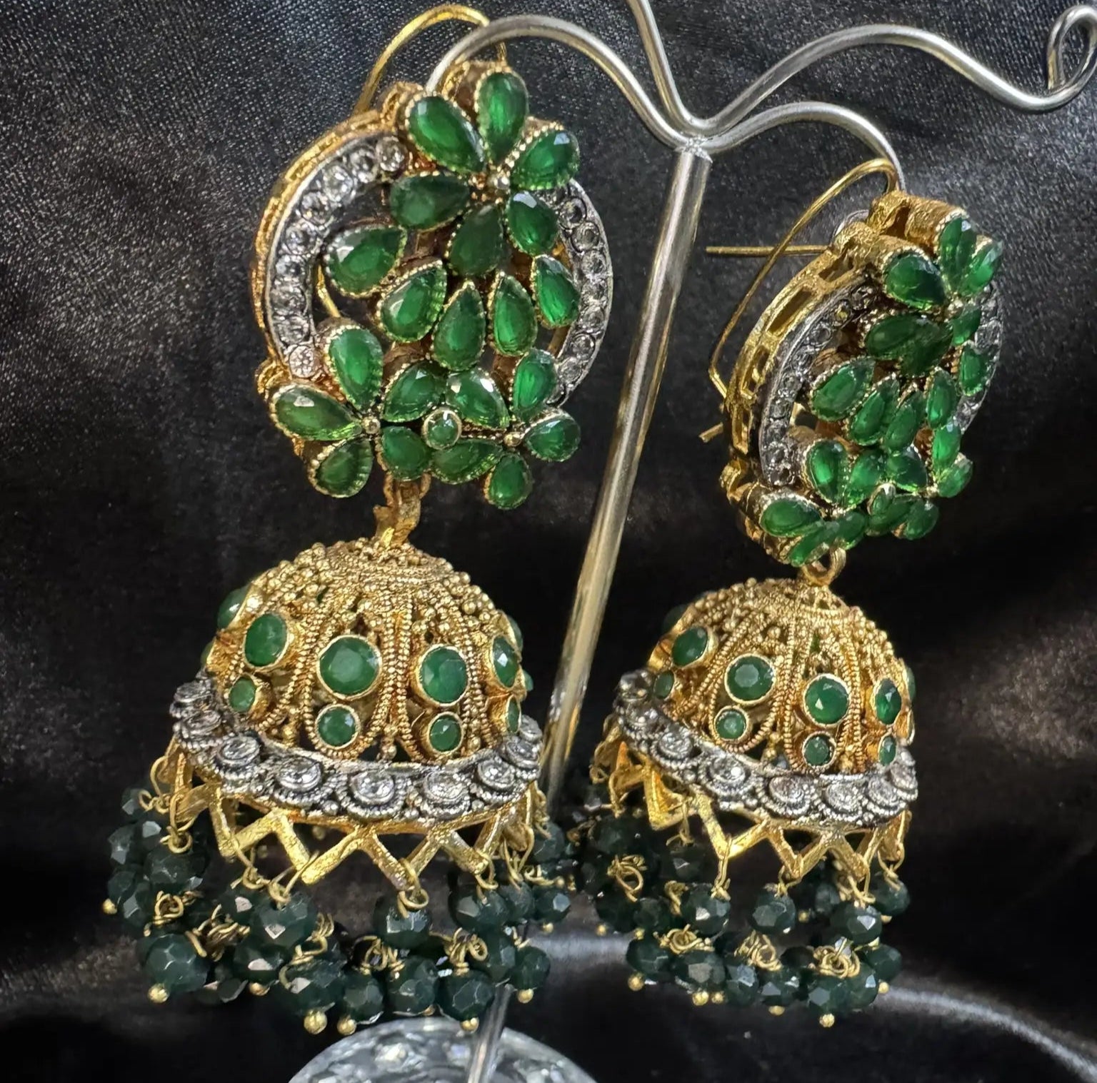 left view of Pakistani design gold-plated jhumkay with green colored gemstones and floral accents