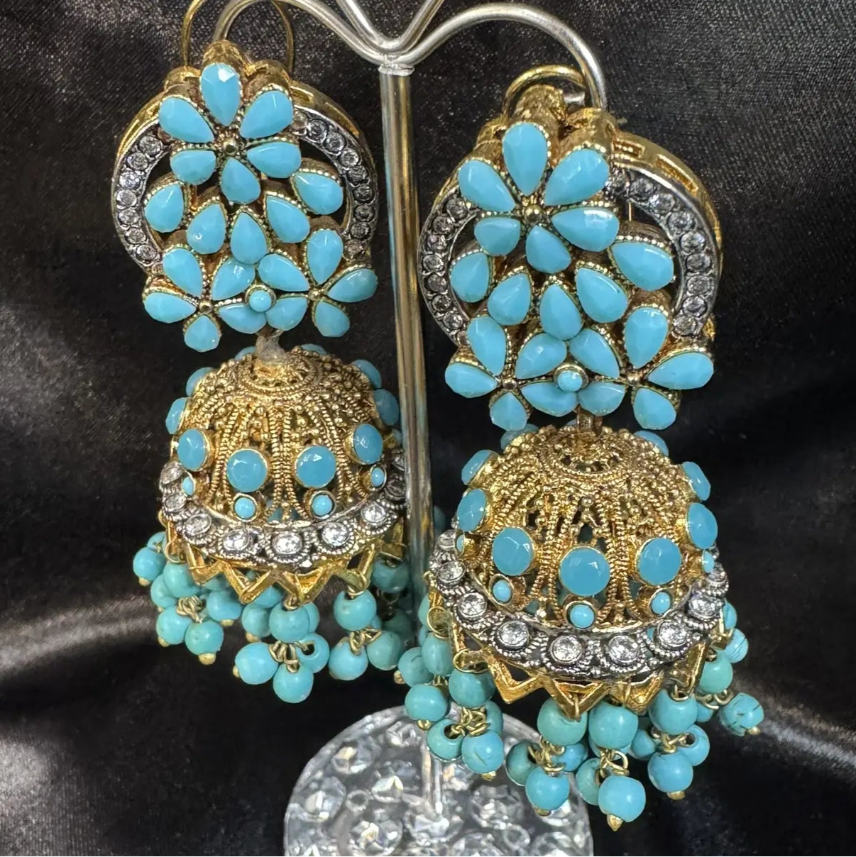 right side view of Pakistani design gold-plated jhumkay with turquoise colored gemstones and floral accents