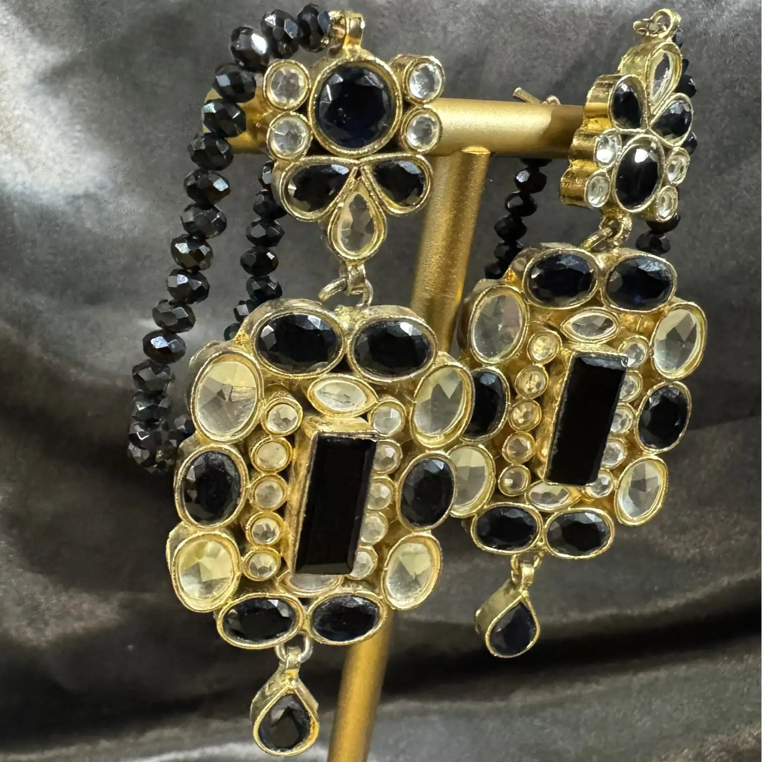 earrings with gold and black gemstones on a gray fabric background