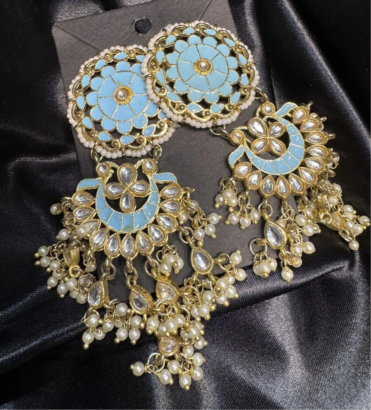 Ornate gold and turquoise earrings on a black satin background