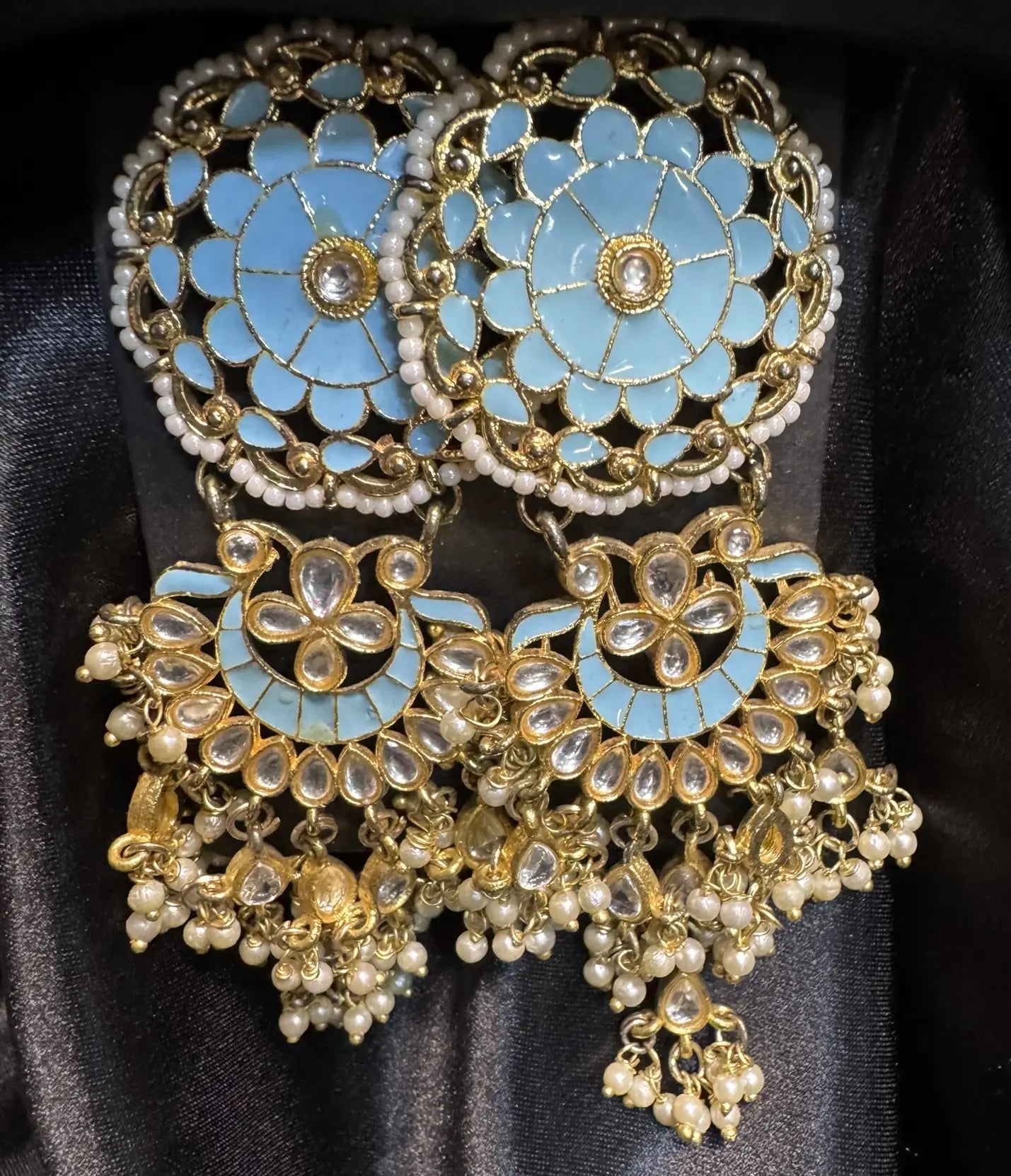 Ornate earrings with turquoise floral design and gold accents on a black background