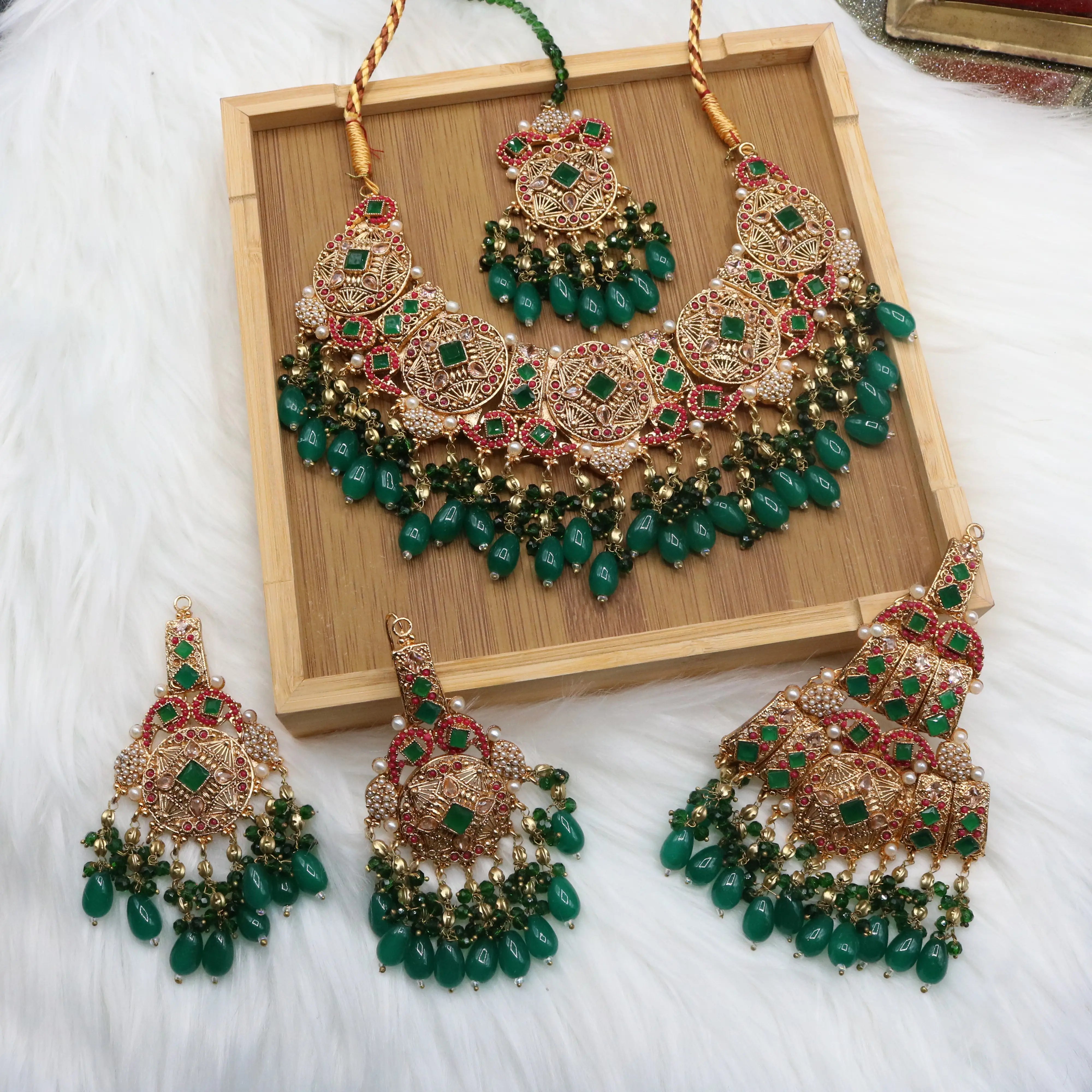 another view of Pakistani bridal set handcrafted with intricate gold-plated detailing, this traditional jewelry set features red stone inlays, sparkling accents, and rich green bead drops
