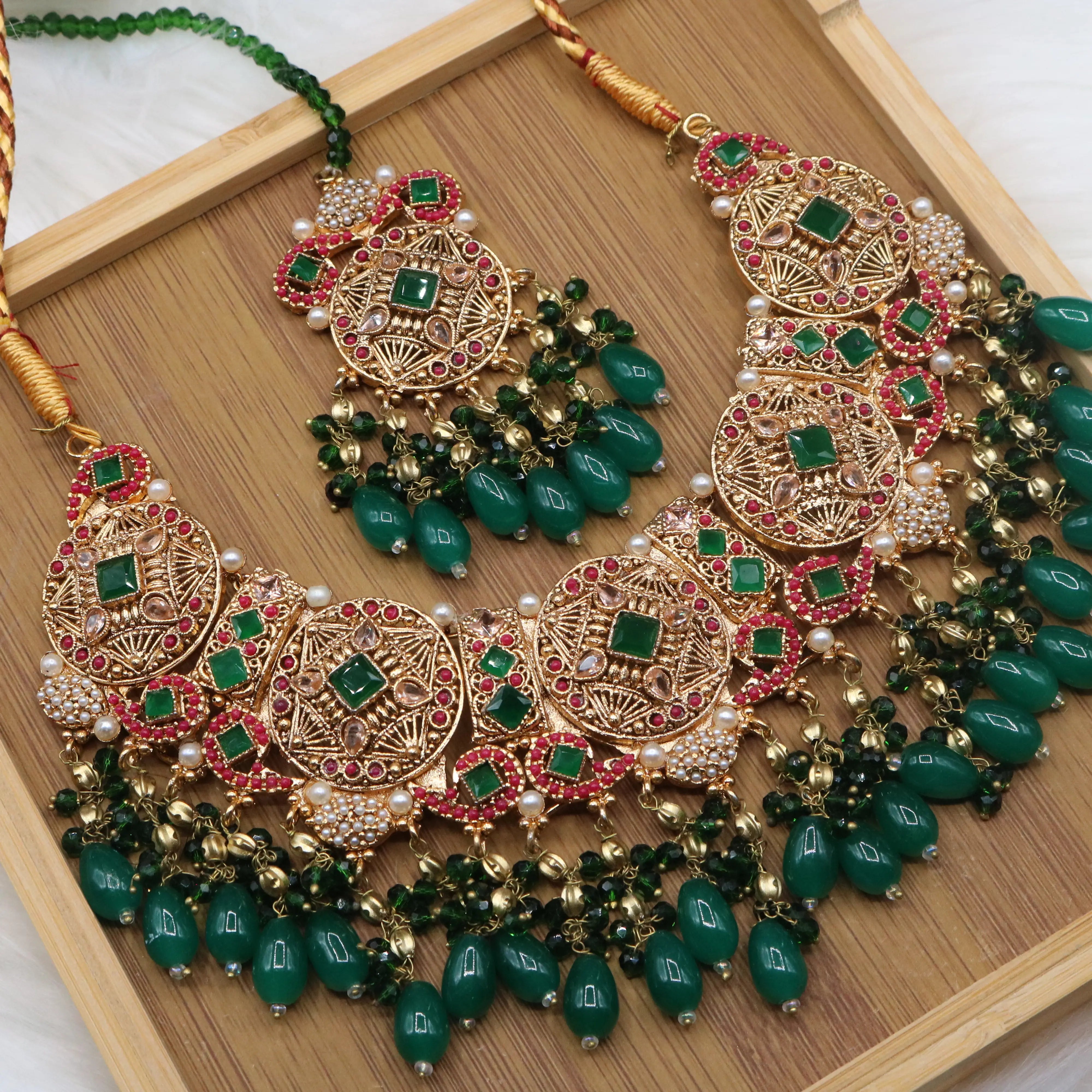 necklace view of Pakistani bridal set handcrafted with intricate gold-plated detailing, this traditional jewelry set features red stone inlays, sparkling accents, and rich green bead drops