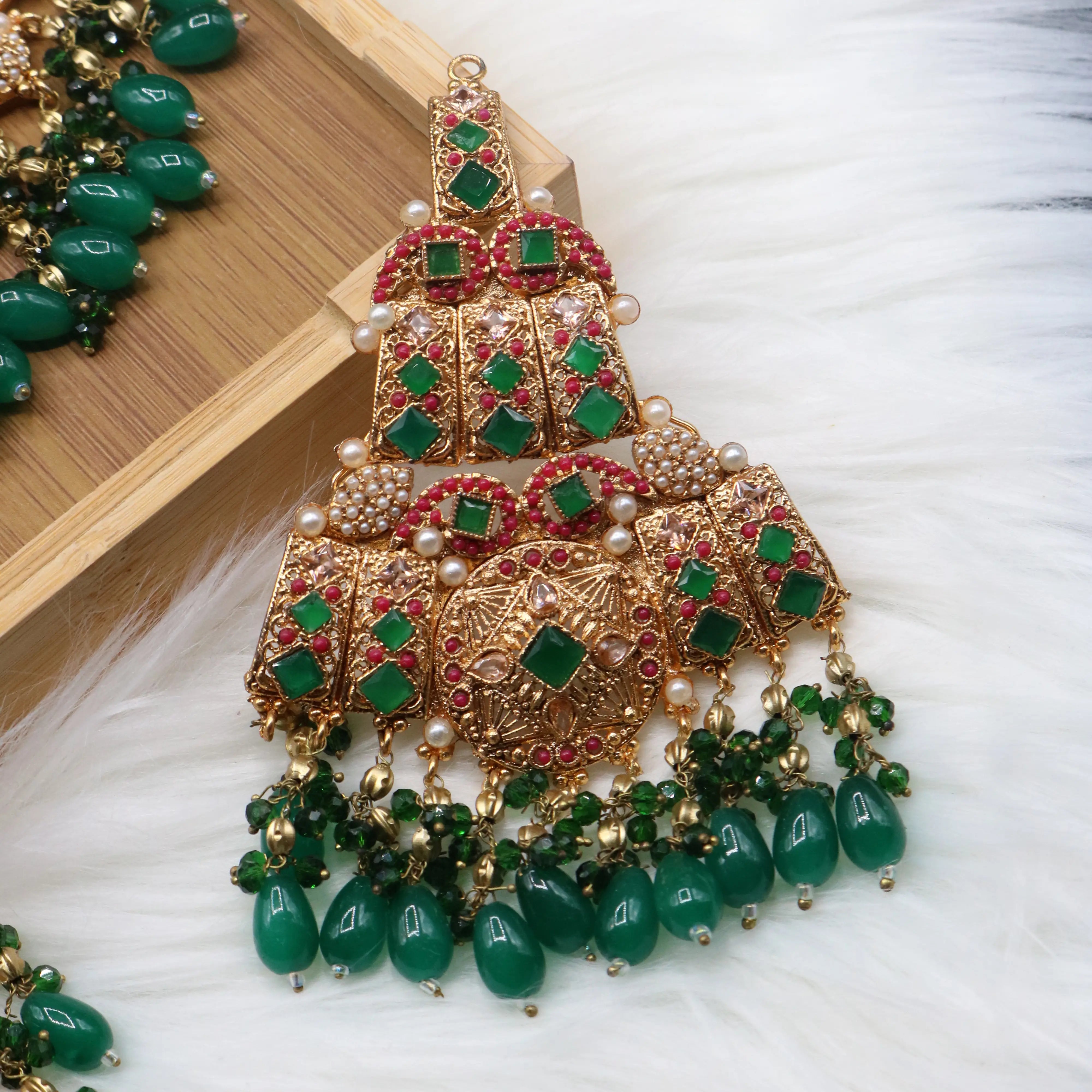 Jhoomer view of Pakistani bridal set handcrafted with intricate gold-plated detailing, this traditional jewelry set features red stone inlays, sparkling accents, and rich green bead drops