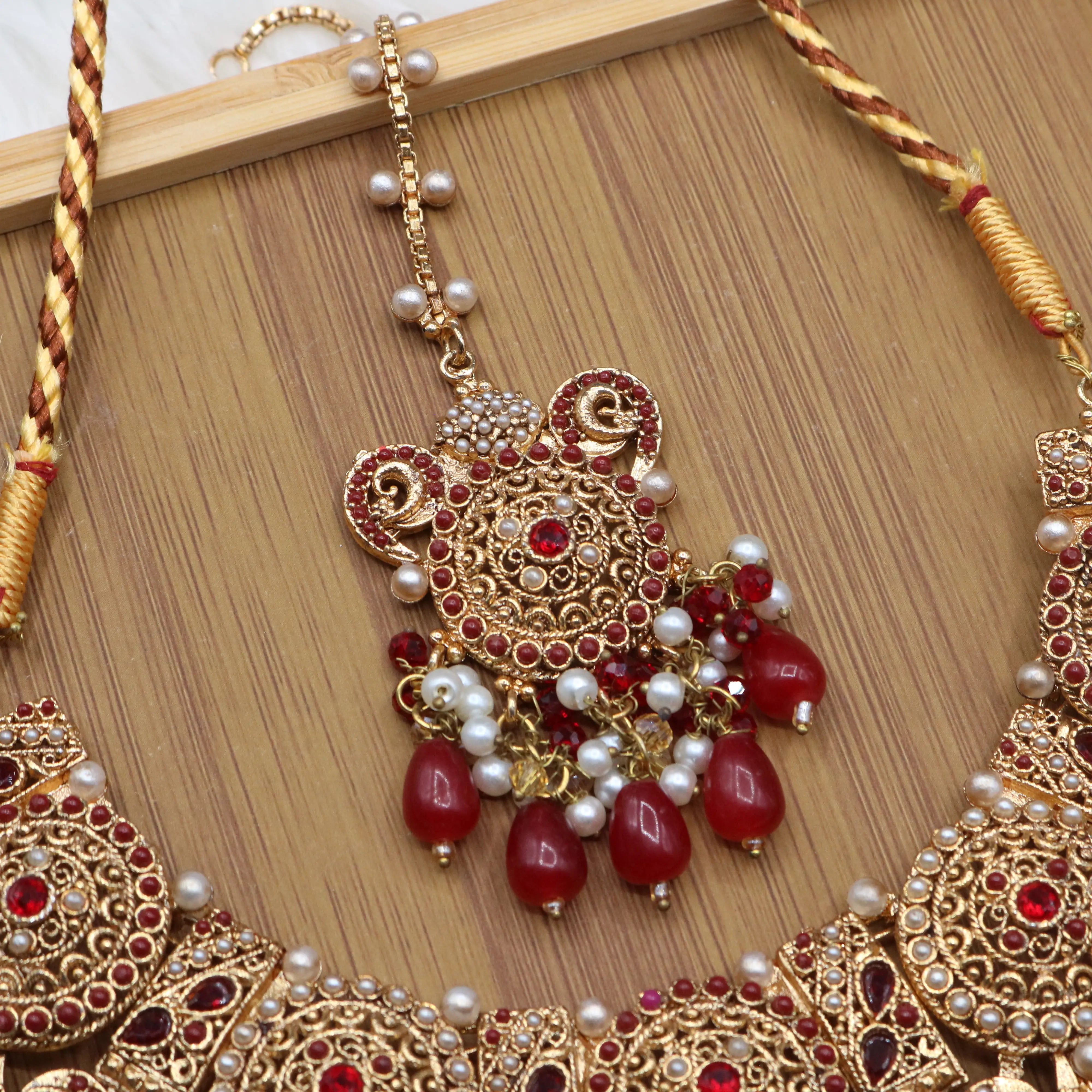 teeka view of Pakistani bridal necklace set with earrings, jhoomer and teeka in red and gold
