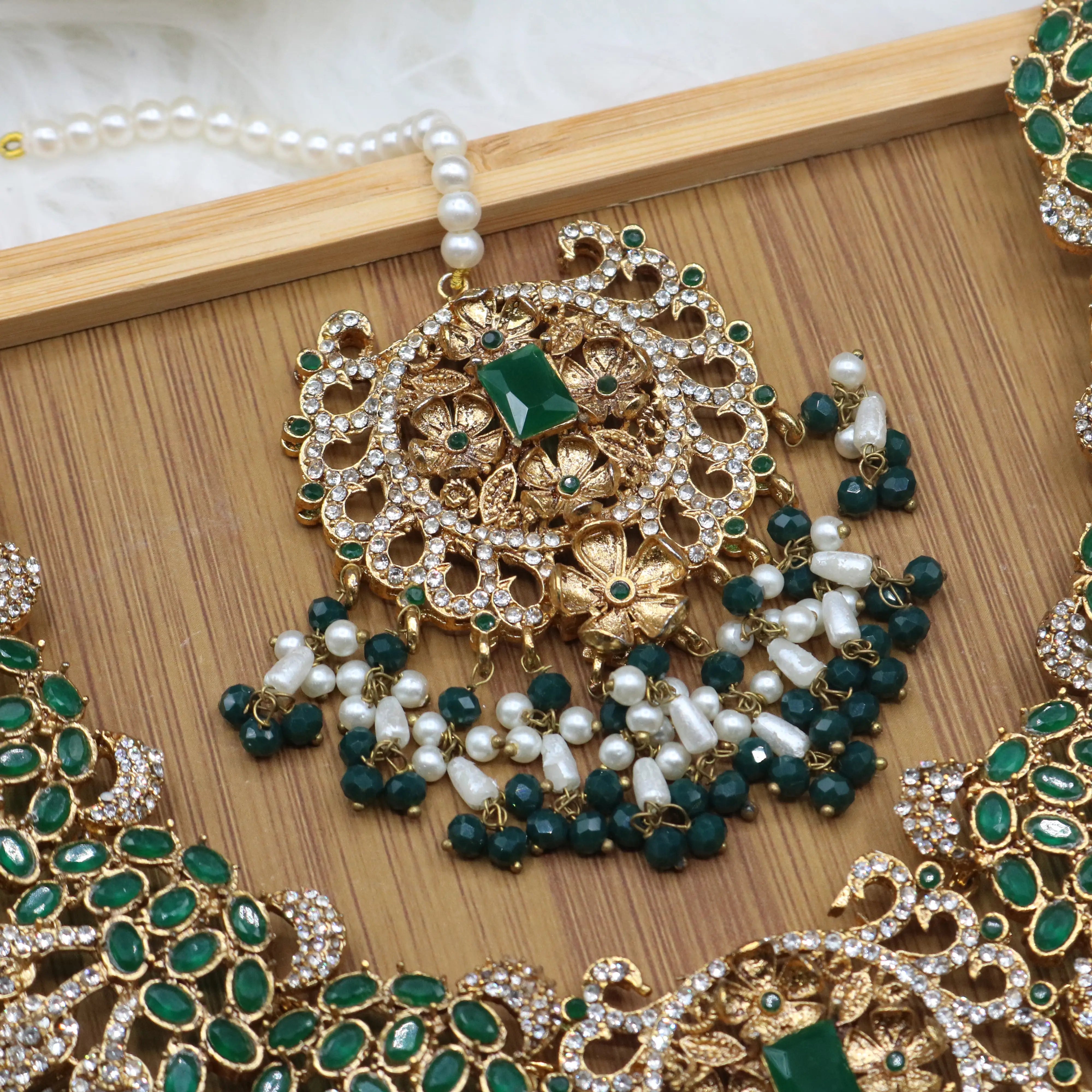 teeka view of Pakistani bridal necklace set with earrings, jhoomer and teeka in green and gold with pearls