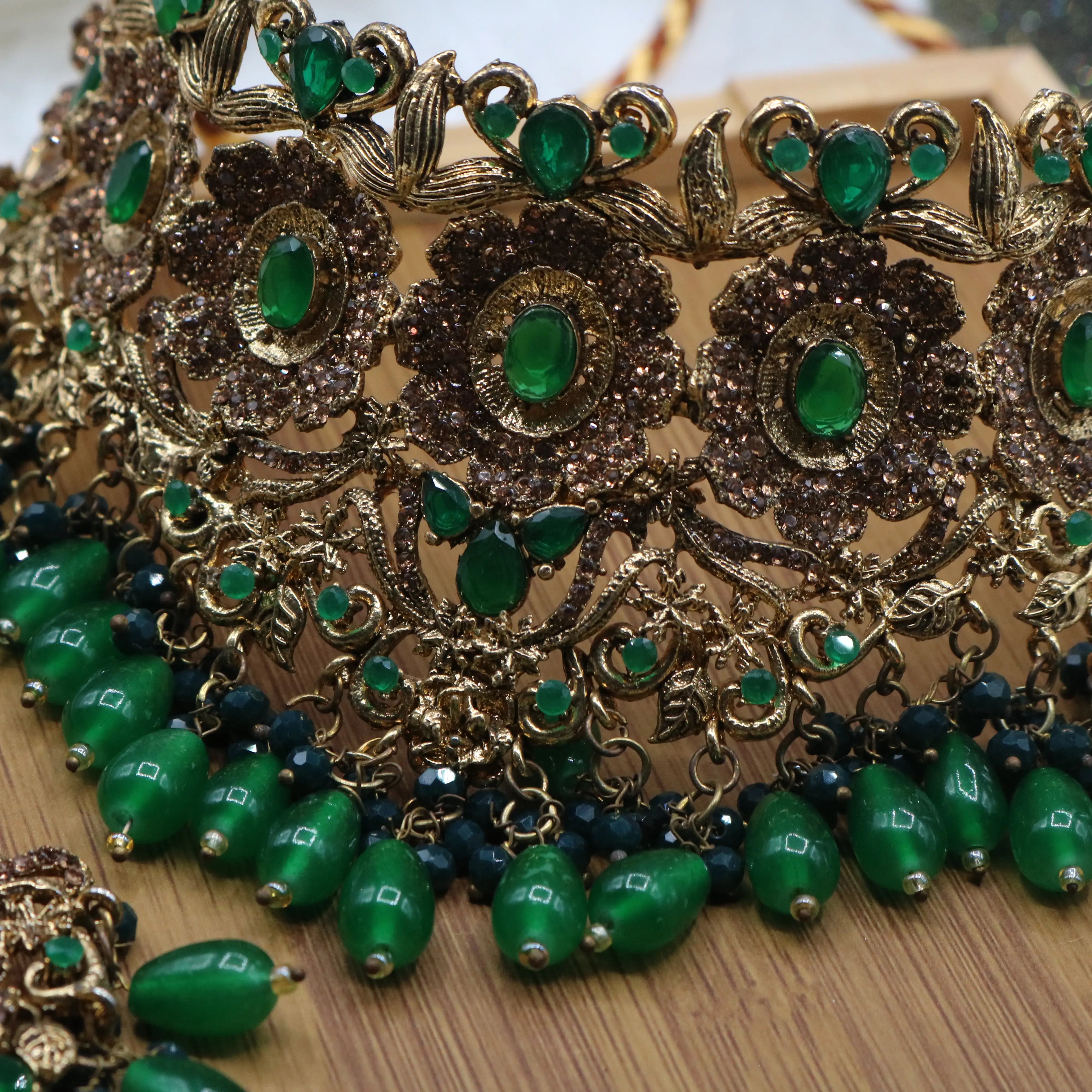 necklace closer view of Pakistani bridal jewelry set with green stones and teeka