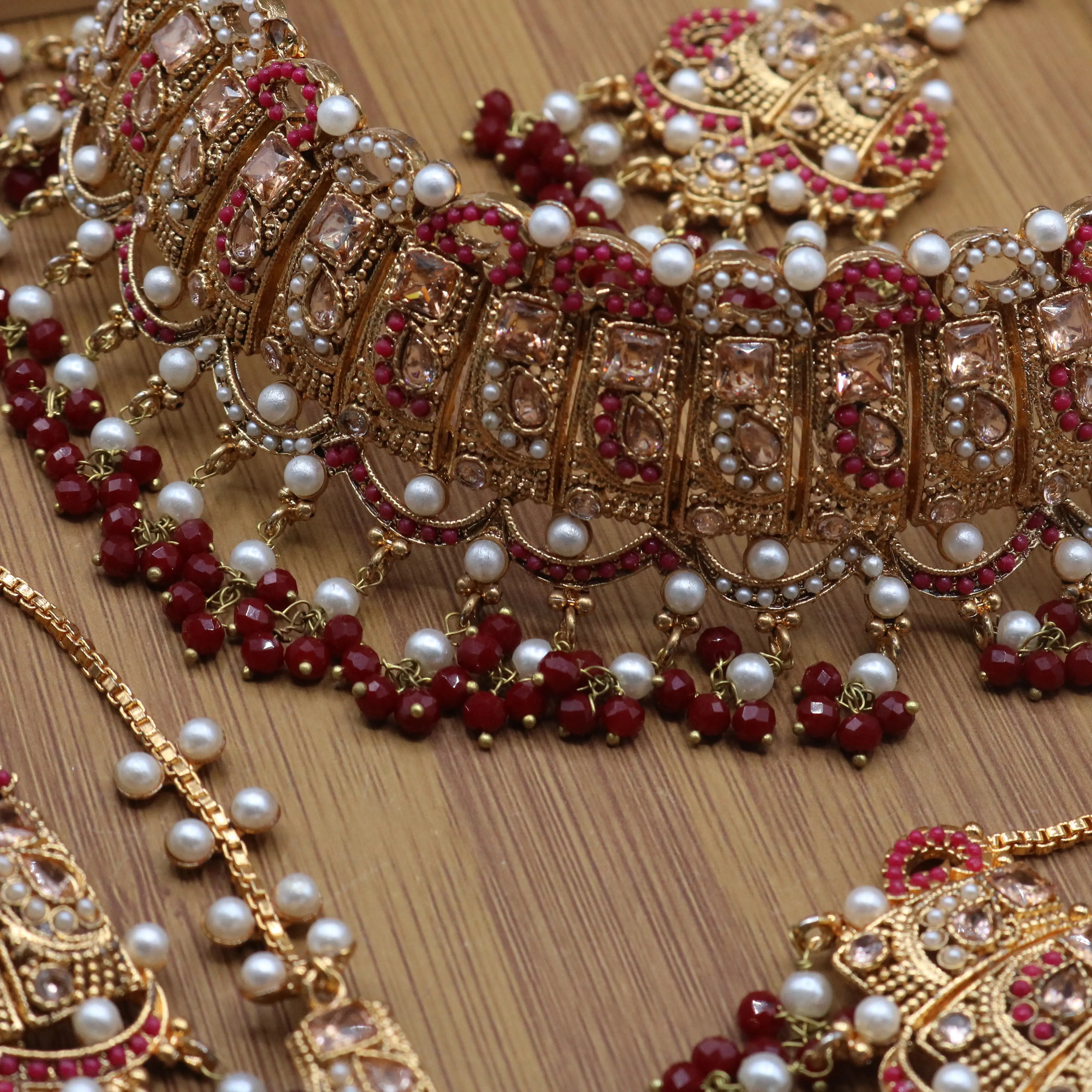 closer necklace view of Pakistani wedding jewelry set with choker, earrings, and jhoomer with red stones