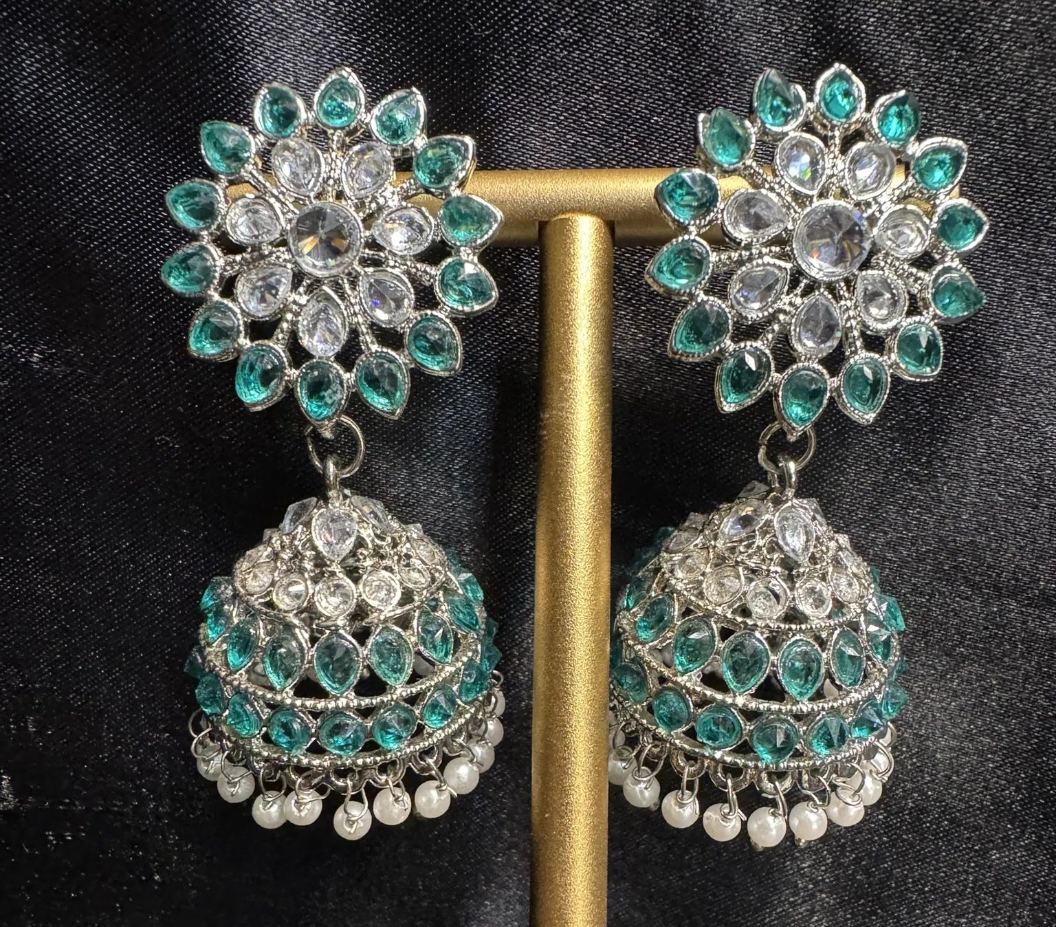 Green jhumkay with white pearl accents on a black background