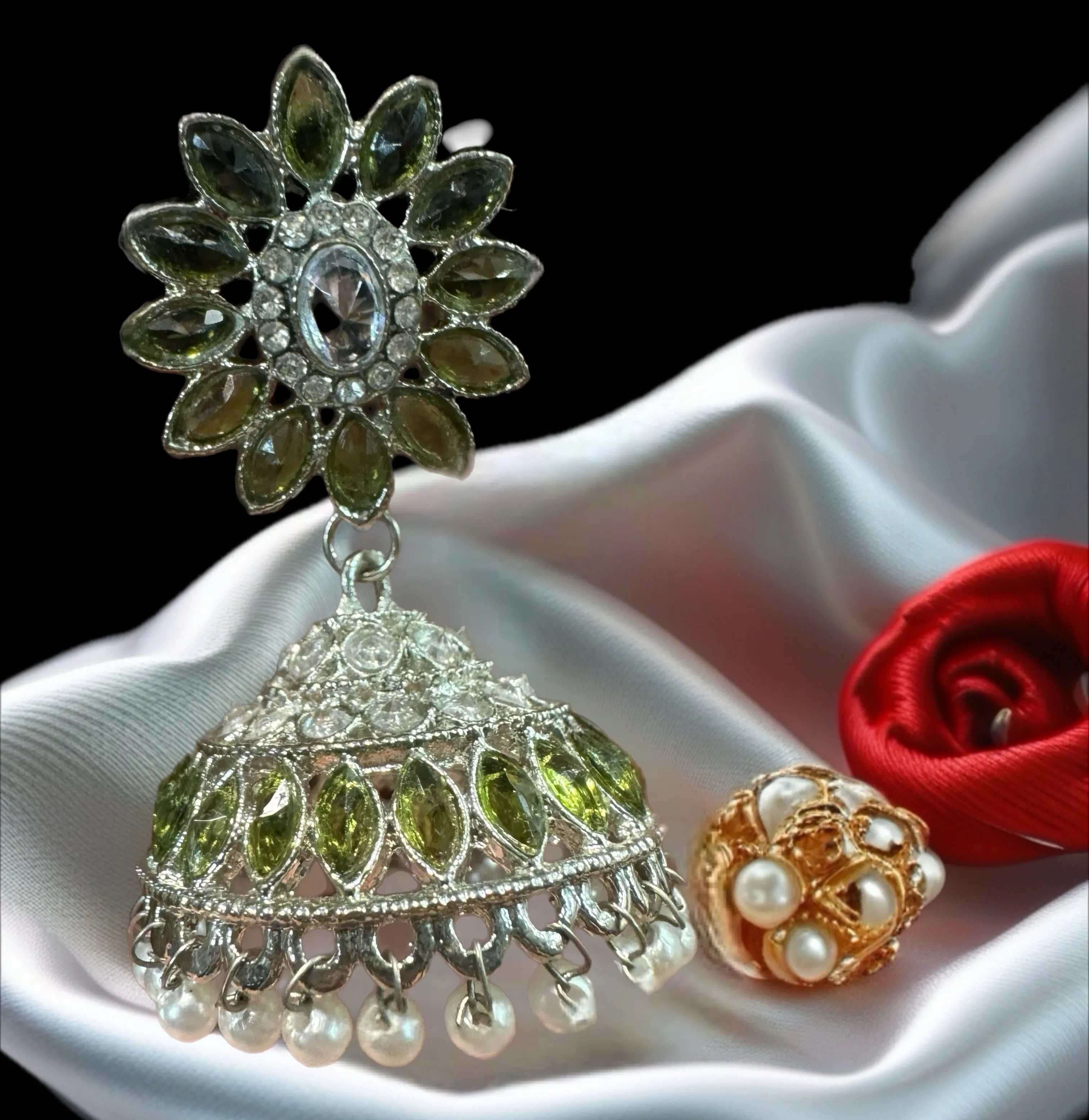 Jhumkay with olive green stones on a white surface.