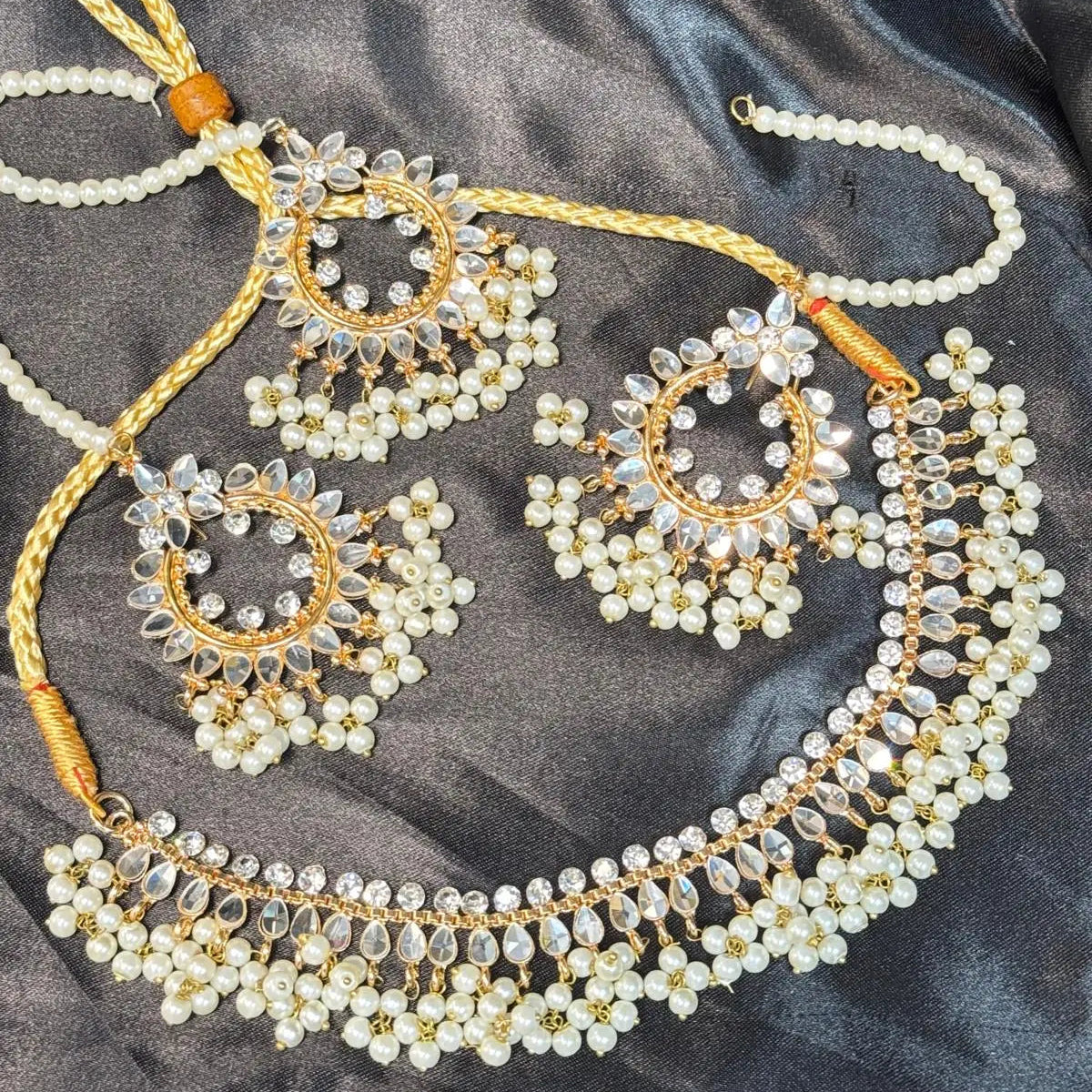 Close-up of JV143 necklace set with pearl and crystal detailing, laid flat on black satin