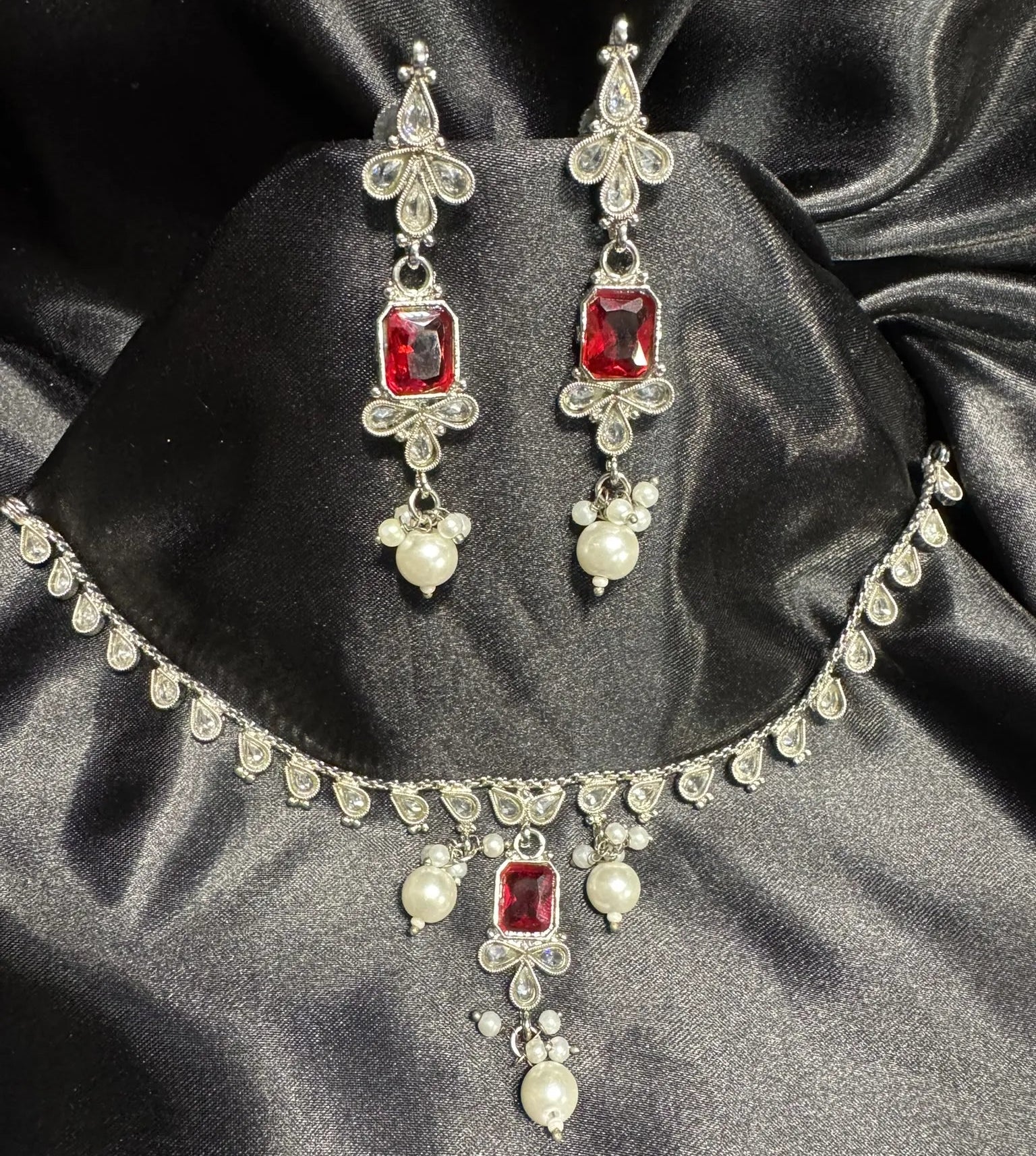 JV148 ruby red and pearl necklace set displayed on black satin, featuring CZ stones in silver finish.