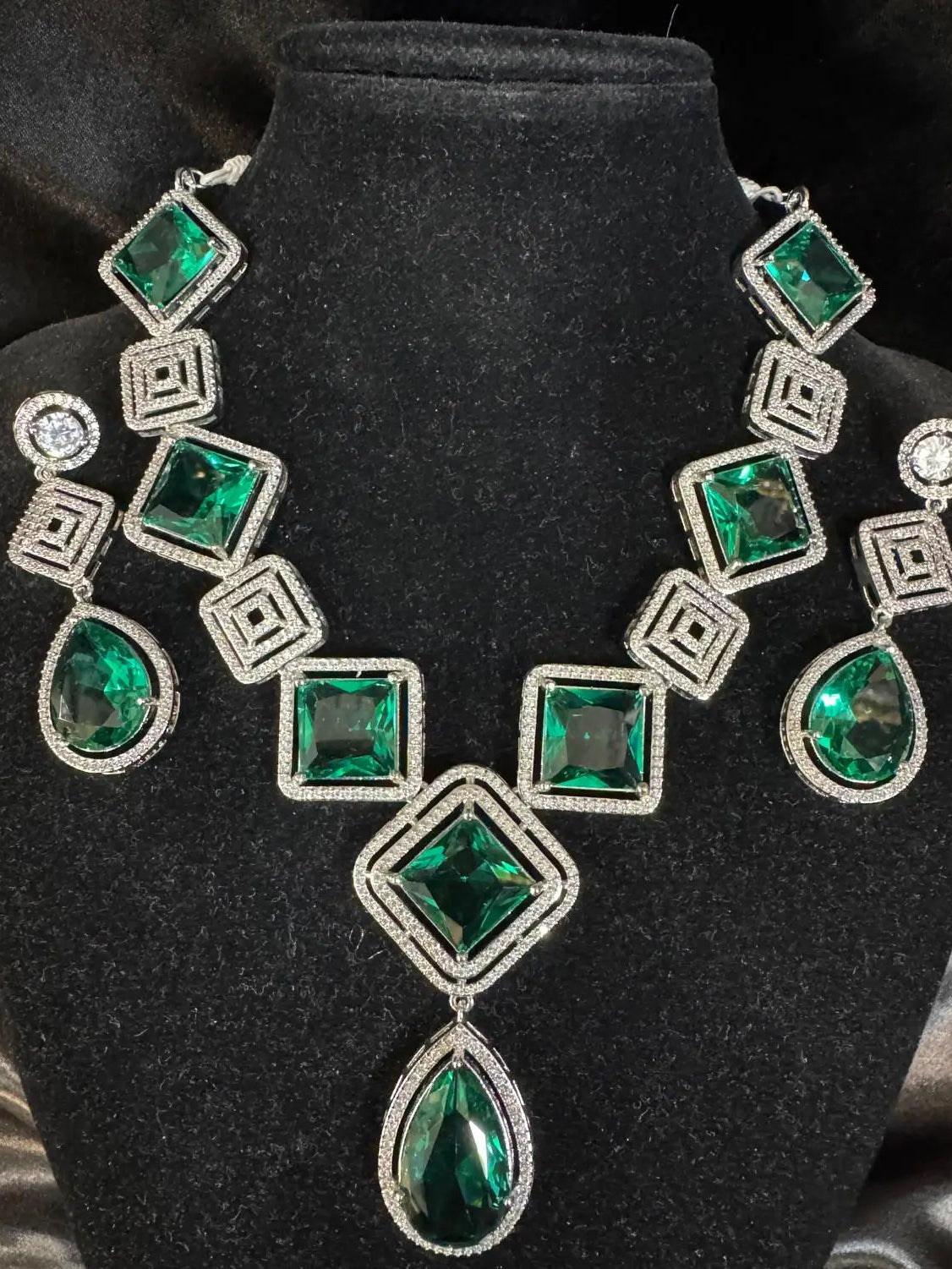 Close-up of JV149 emerald green geometric necklace with teardrop CZ center on black bust.