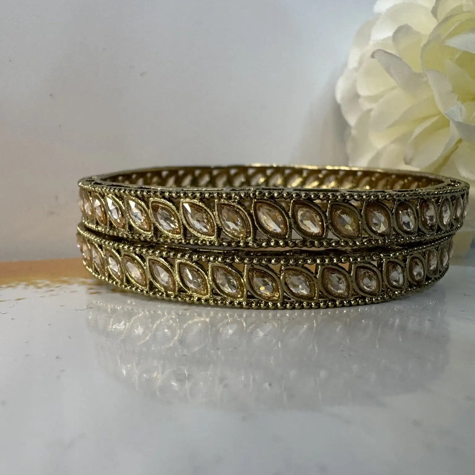 Gold bangles with clear gemstones on a white surface