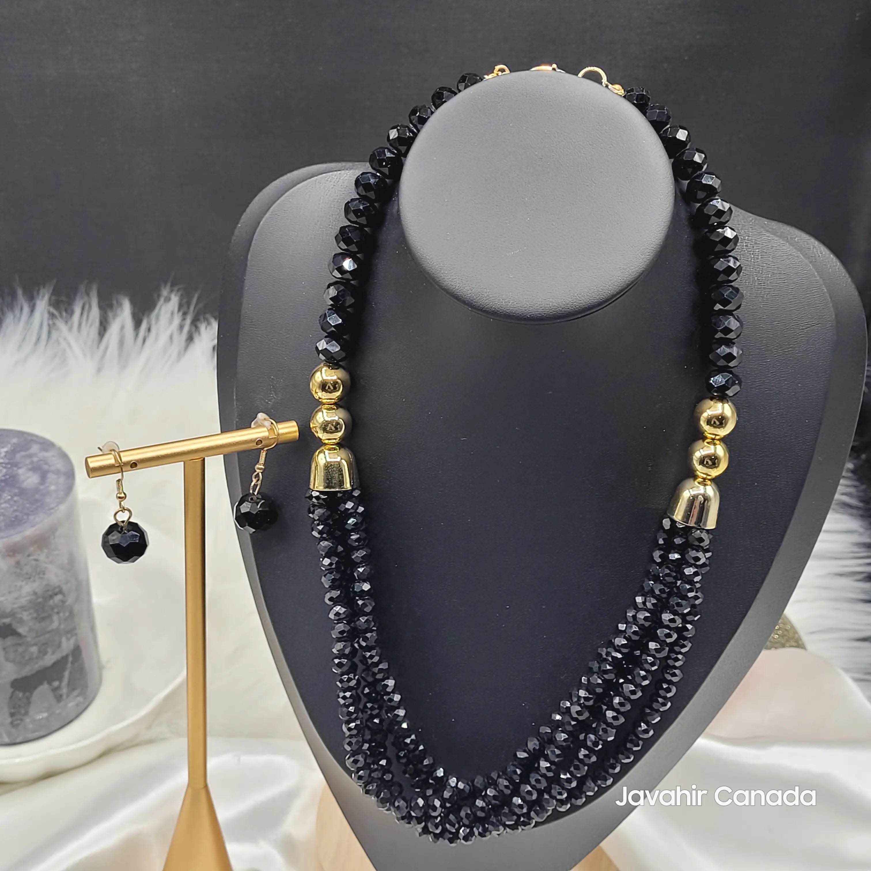 Elegant JV161 necklace in jet black crystal beads, displayed on a black bust. The triple-strand design is paired with gold-tone beads and a matching black earring.
