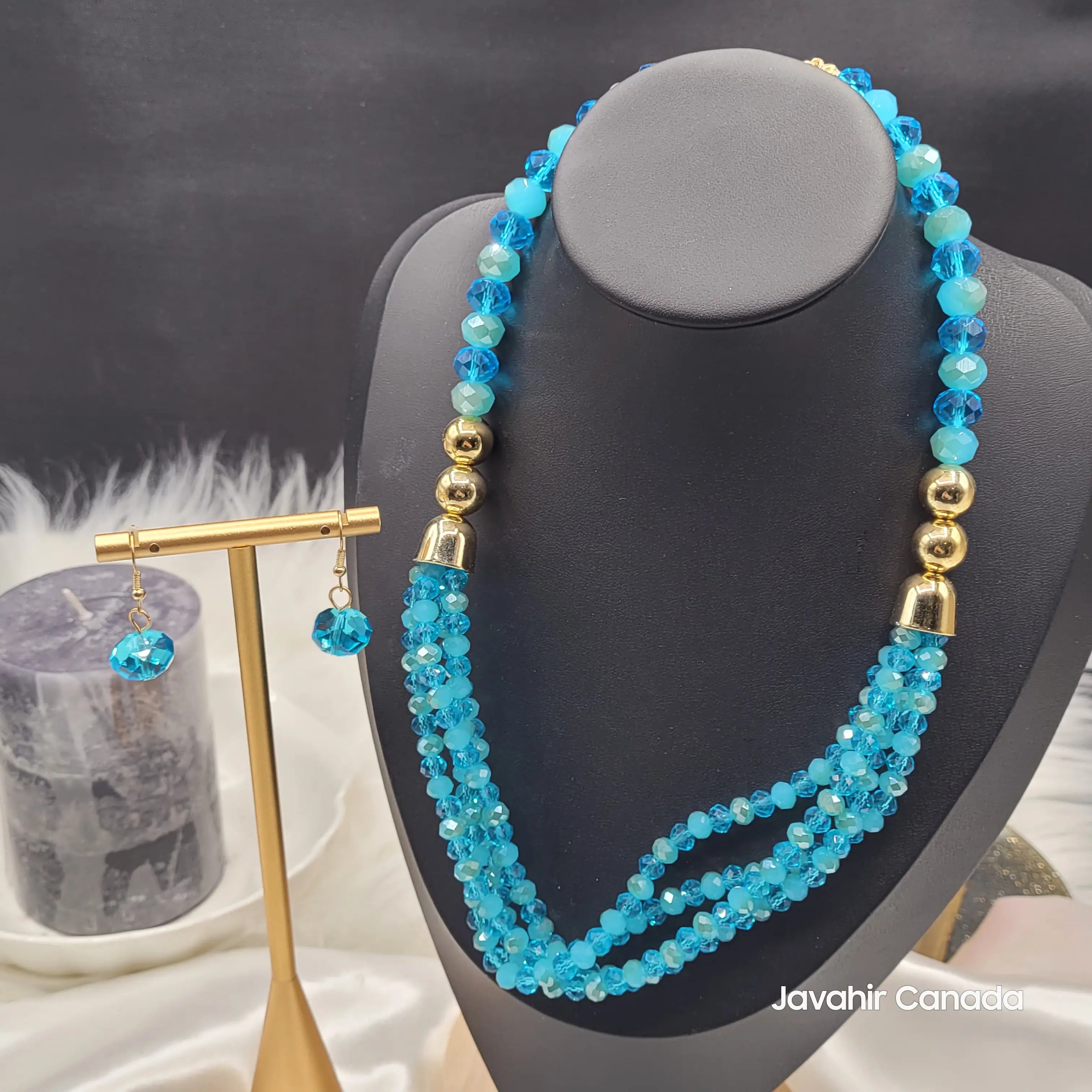 Front view of the JV161 necklace in rich sapphire blue crystal beads, accented with gold-toned connectors and paired with matching drop earrings on a gold stand.