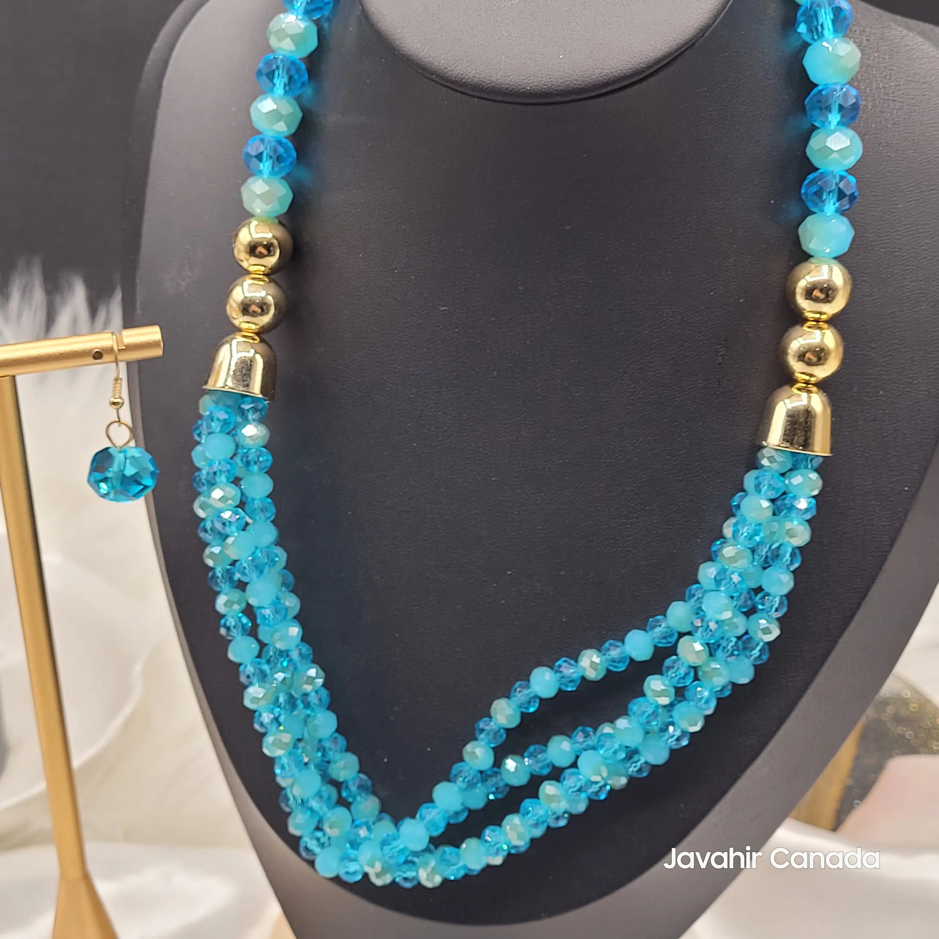 Close-up of the deep sapphire blue JV161 necklace featuring dazzling dark blue crystal beads in three twisted layers with polished gold spacers and a matching earring.