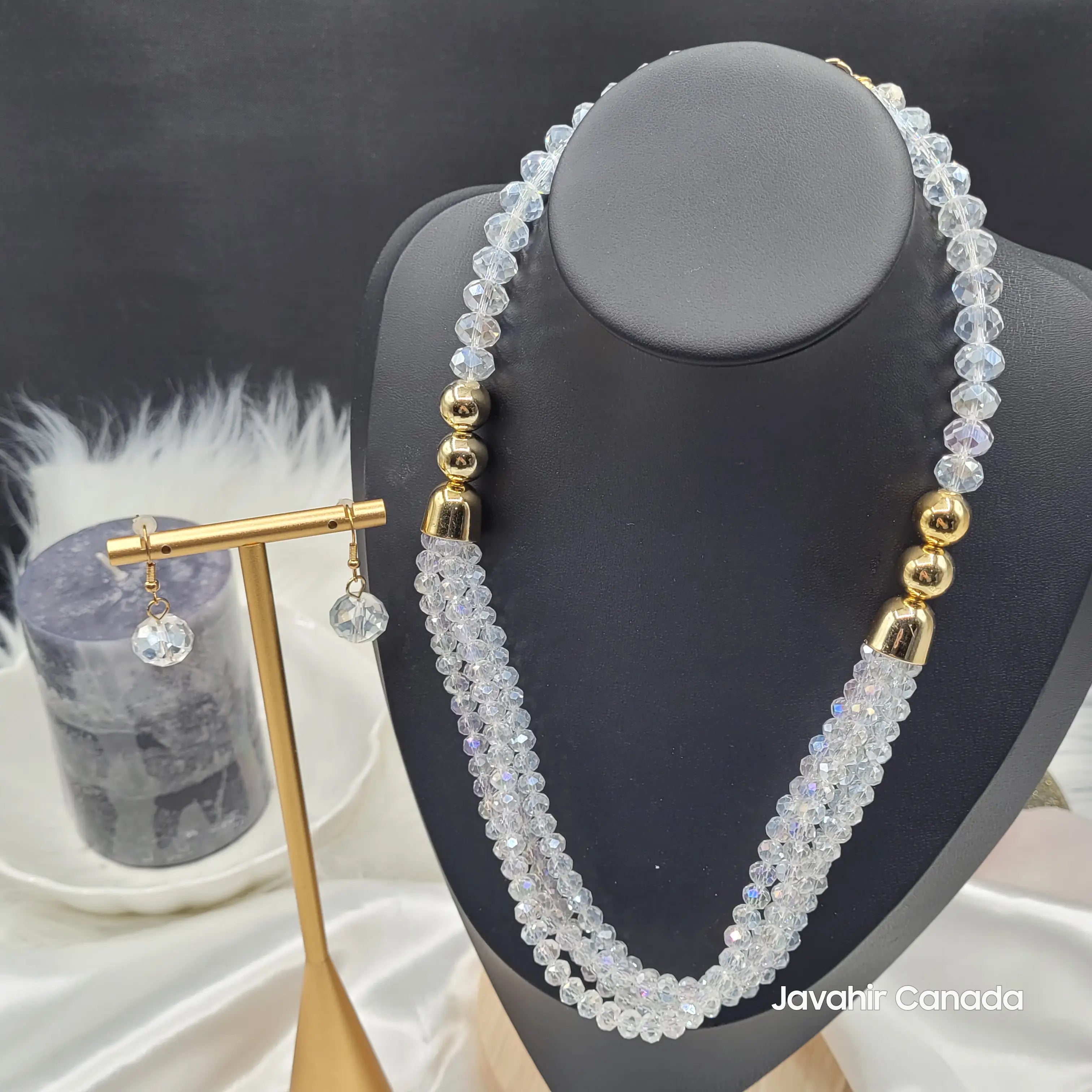 Front view of the JV161 necklace in iridescent clear crystal beads, styled with gold round connectors and a pair of matching drop earrings shown on a gold stand.