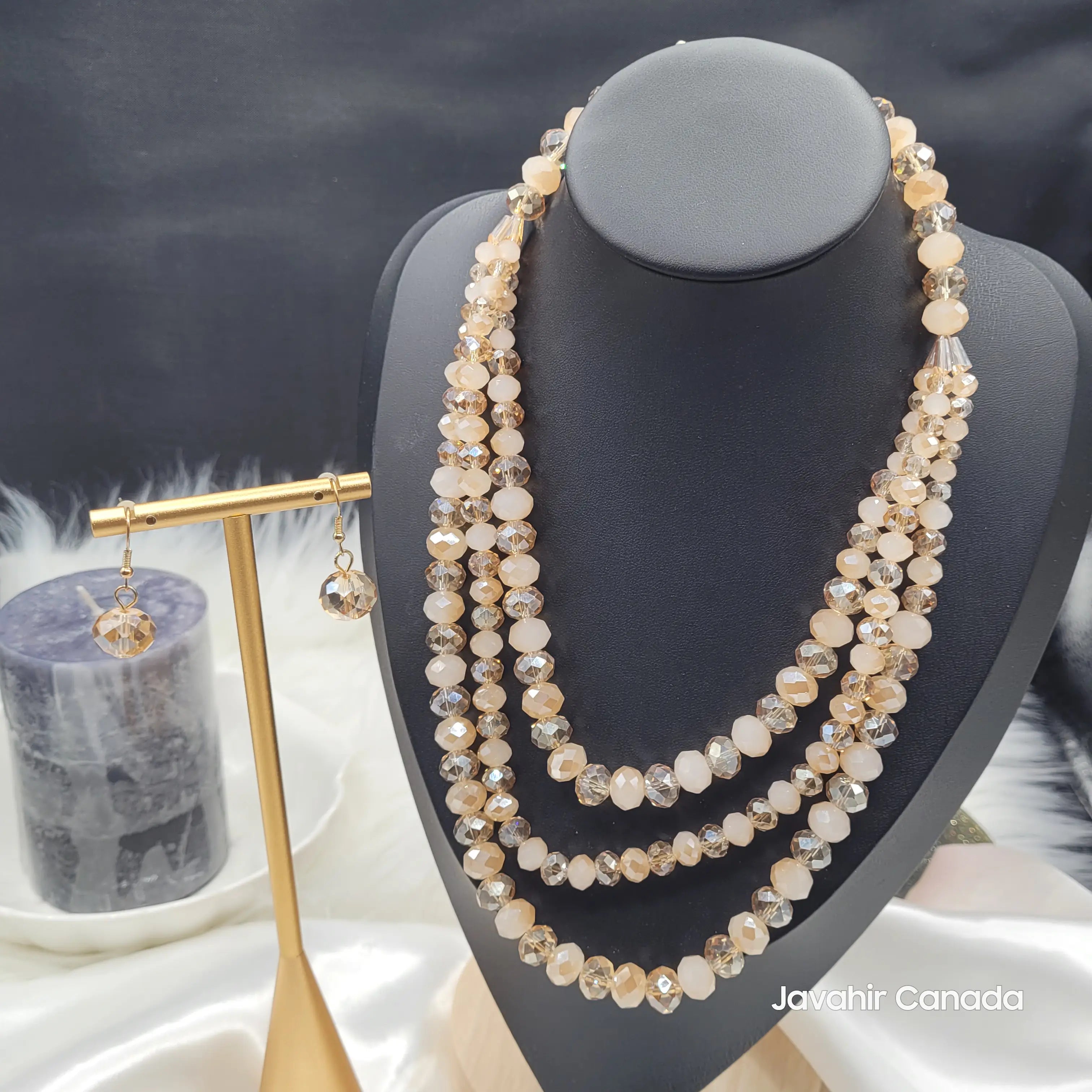 Front display of the JV162 necklace set in warm champagne beige tones, with golden-brown faceted beads and coordinated earrings, presented on a bust and earring stand.