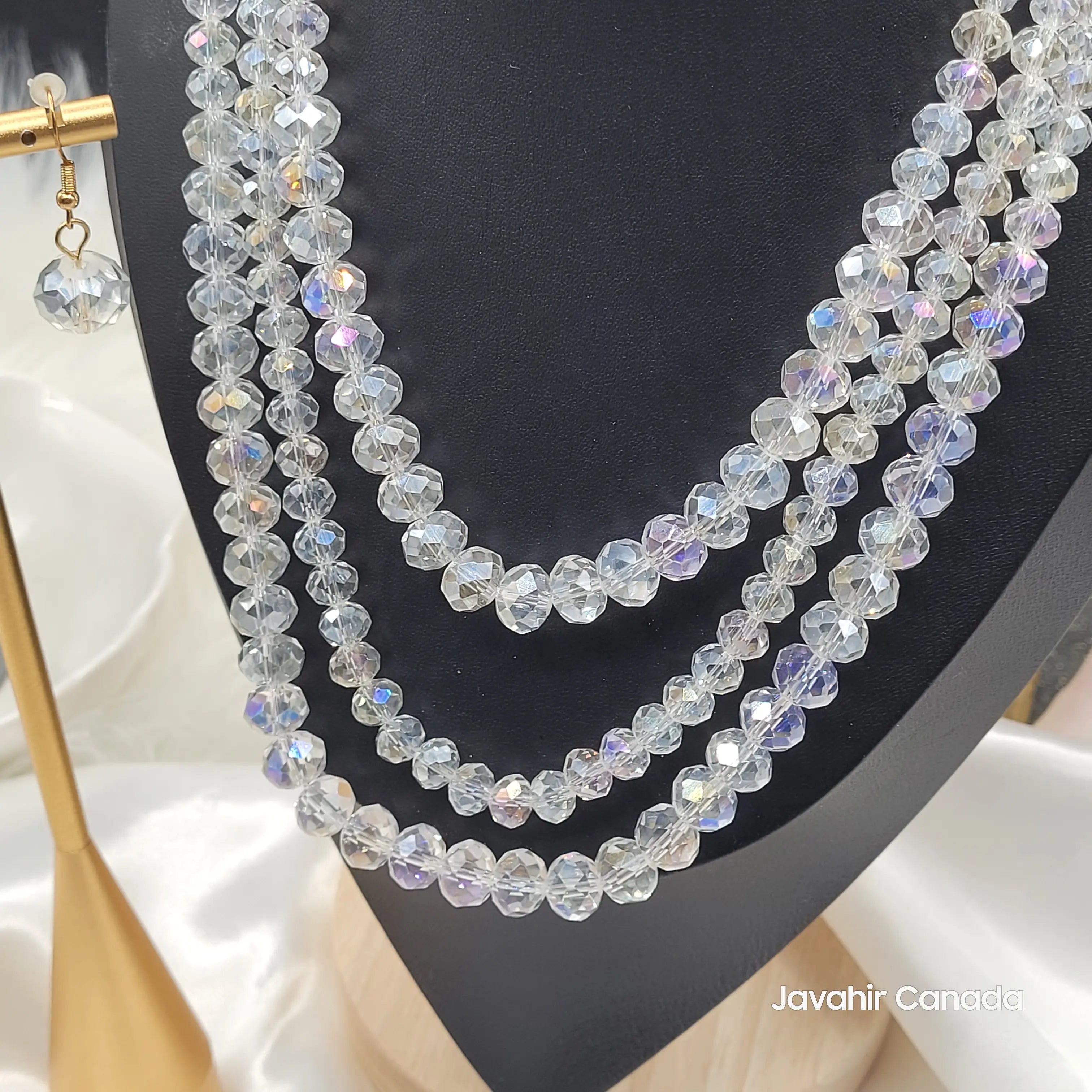 Close-up view of the iridescent clear JV162 necklace with multicolored reflections on faceted beads, arranged in four strands and paired with a crystal earring.