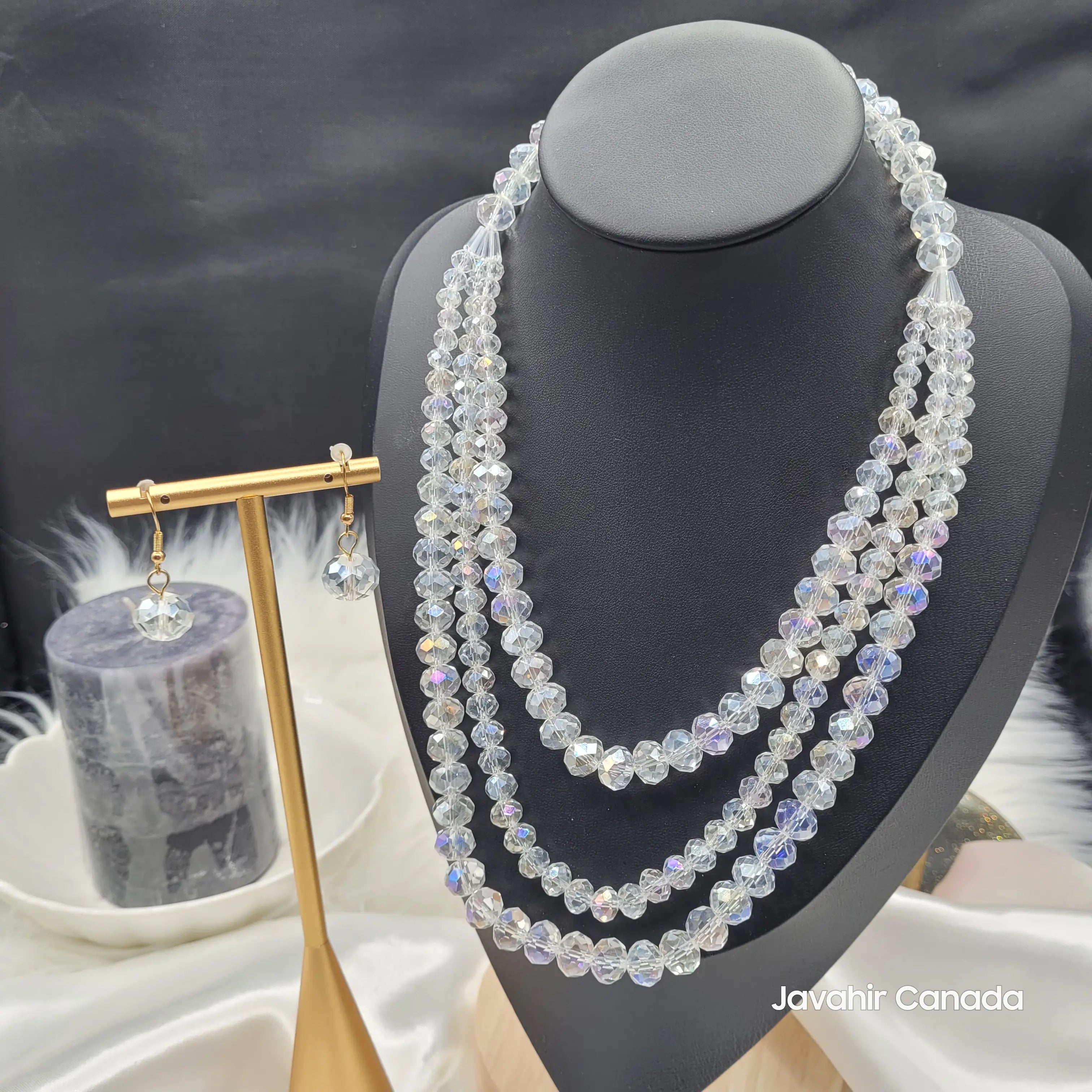 JV162 crystal clear necklace set with faceted beads that reflect rainbow hues, featuring a four-layer graduated necklace and matching drop earrings on a black display bust.