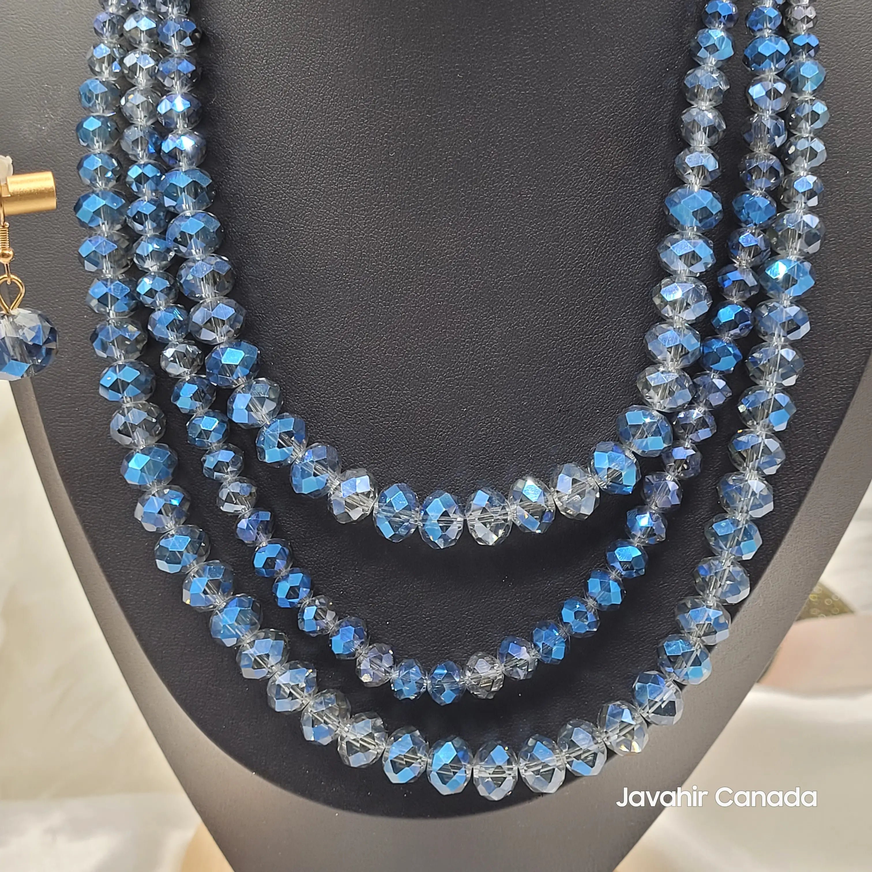Close-up of the JV162 necklace in a sapphire blue ombré design with shimmering faceted beads, arranged in four strands and paired with a matching blue crystal earring.