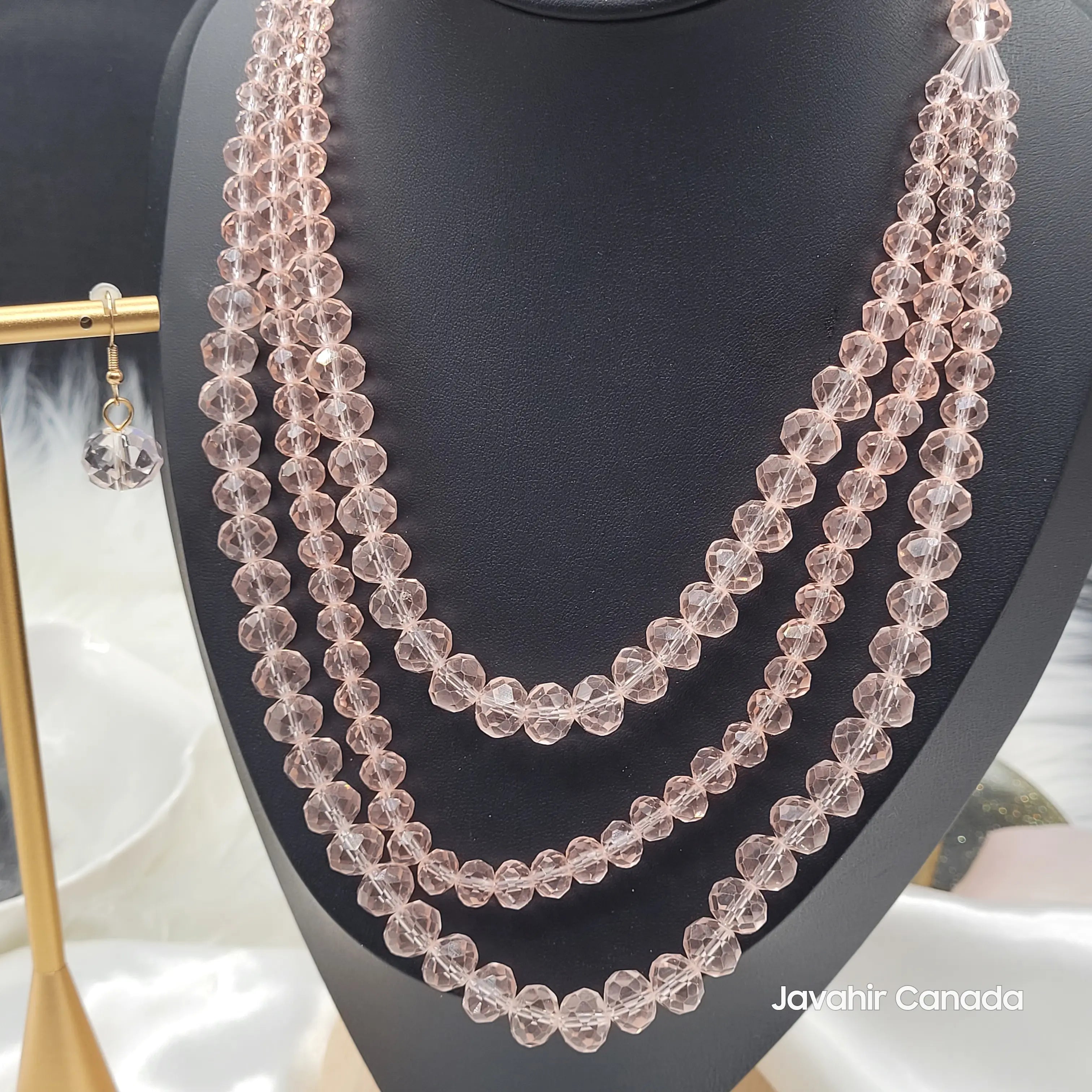Close-up of JV162 necklace in translucent rose pink crystal beads with a soft shimmer, showcasing layered beaded strands and a coordinating pink crystal earring.