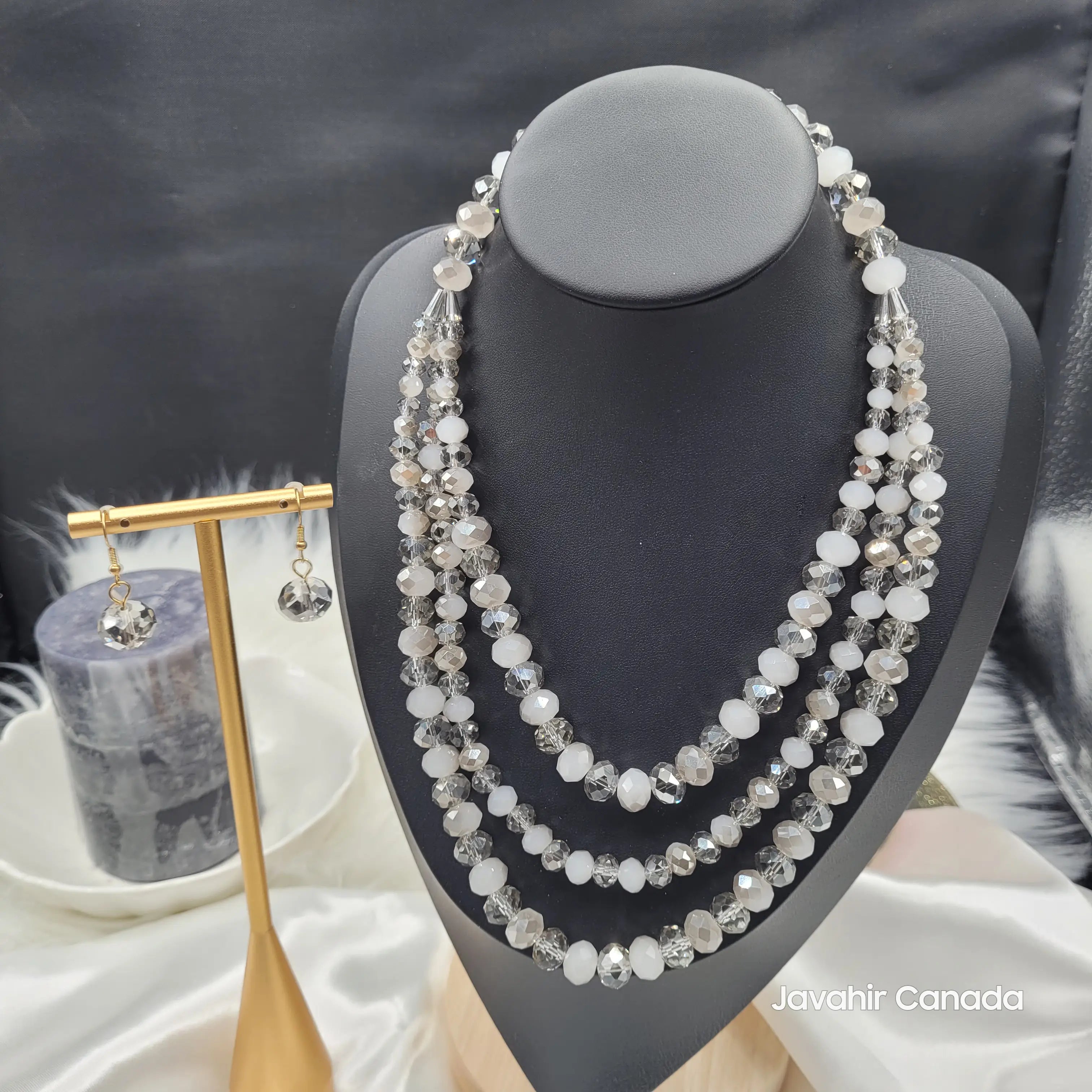 JV162 necklace featuring a four-layered design with alternating white and smoky grey faceted crystal beads, paired with coordinating grey crystal drop earrings on a display bust.