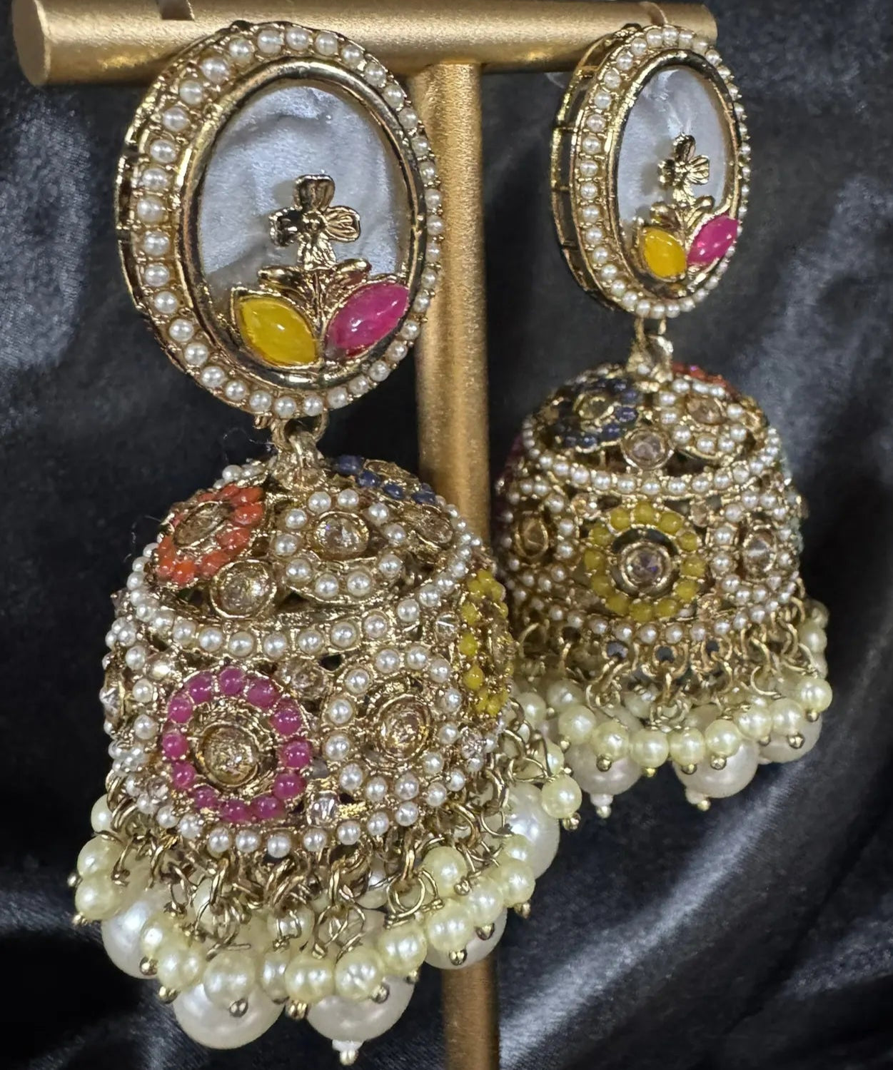 Ornate earrings on a stand against a dark background