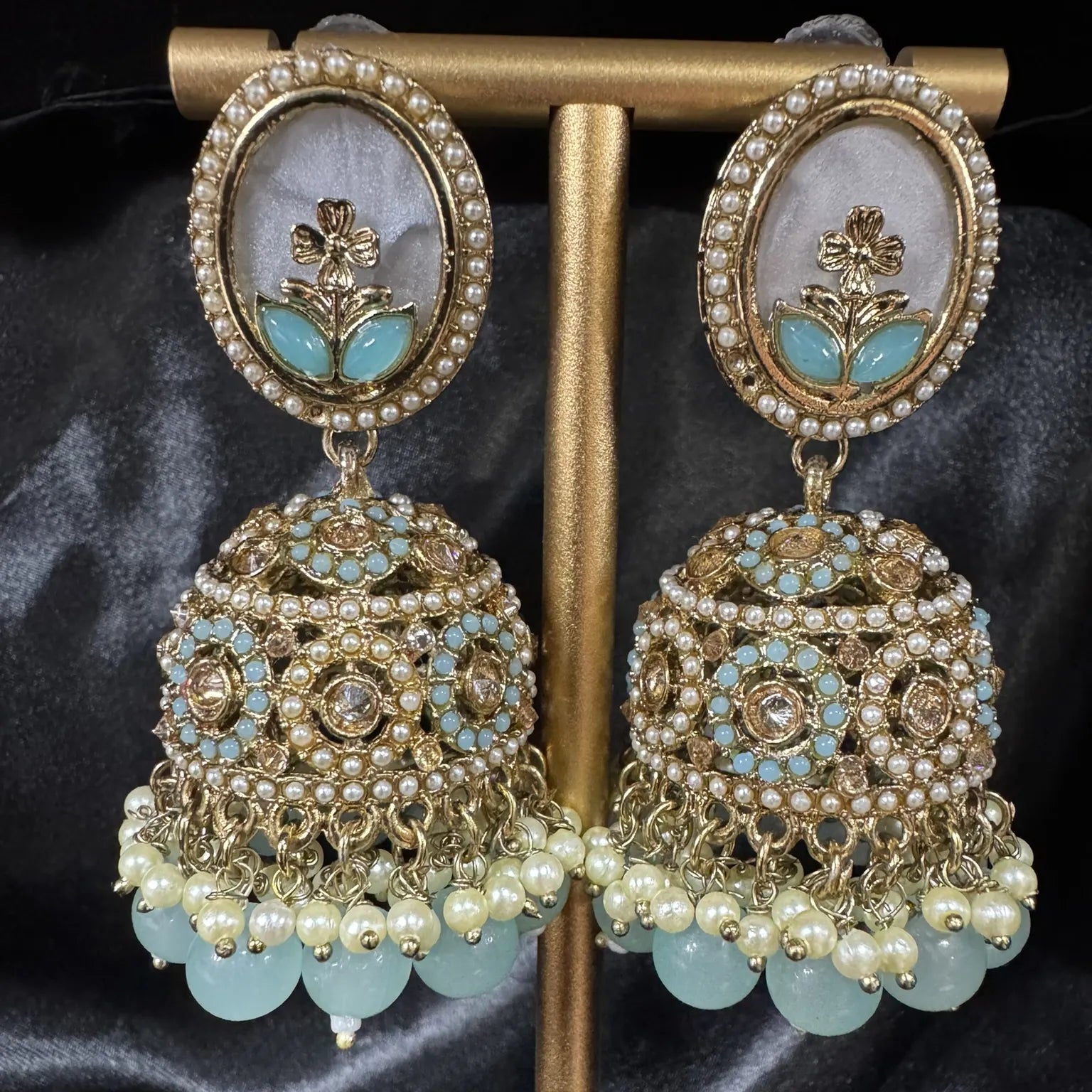 Ornate earrings with floral design on a dark fabric background