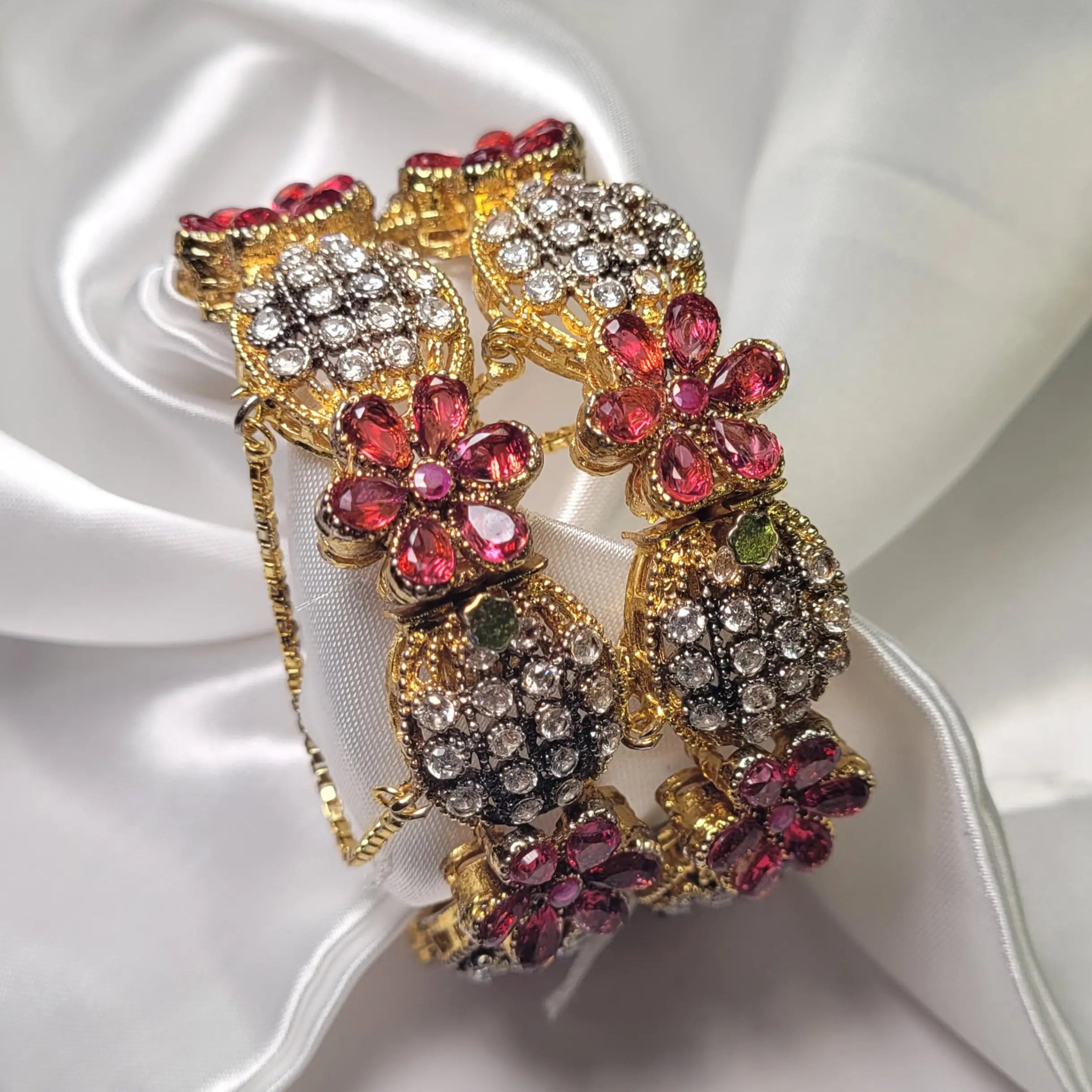 top view of Pink floral design bangles with crystals on a white fabric background – JV3001 