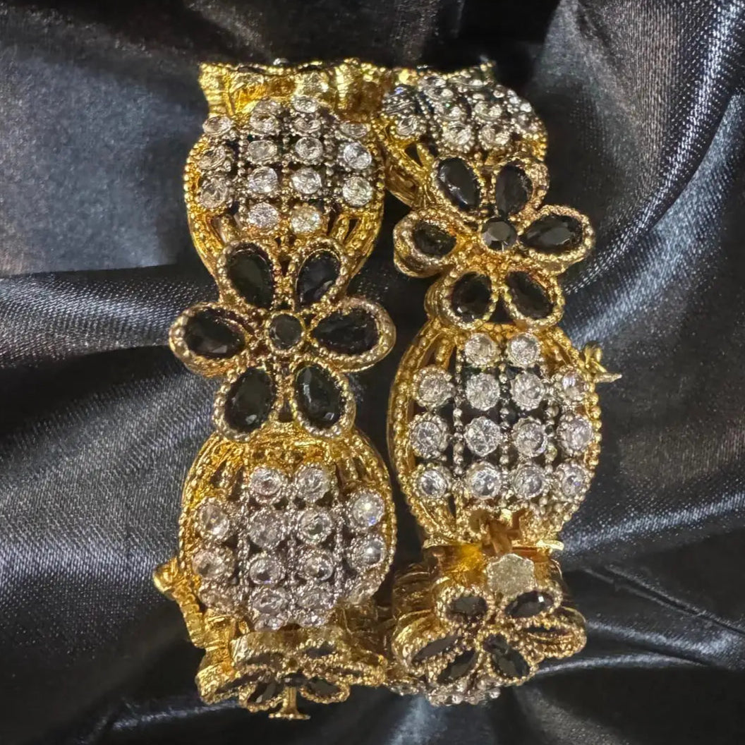 top view of Black floral openable bangles with crystal accents on a black satin background – JV3001