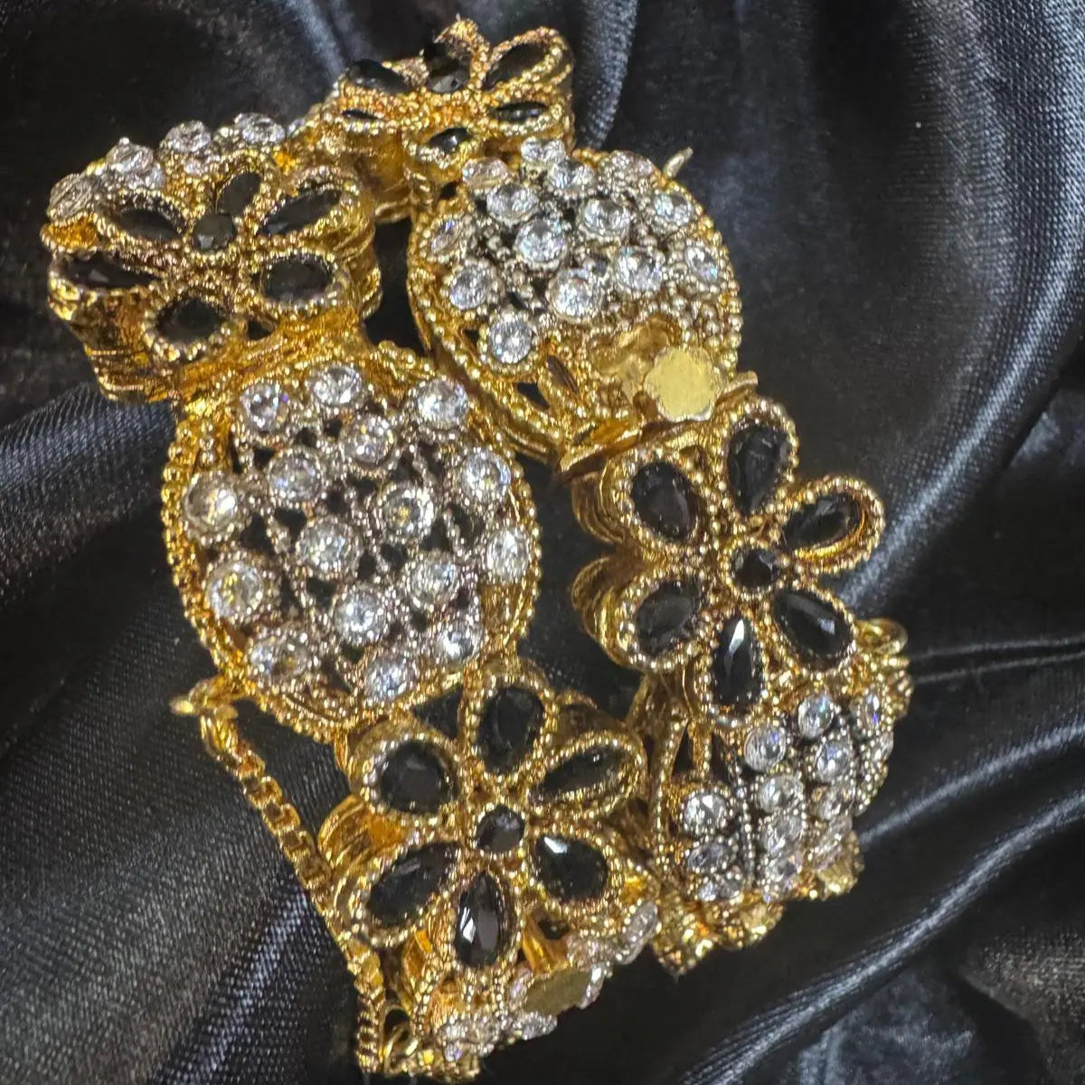 Black floral openable bangles with crystal accents on a black satin background – JV3001