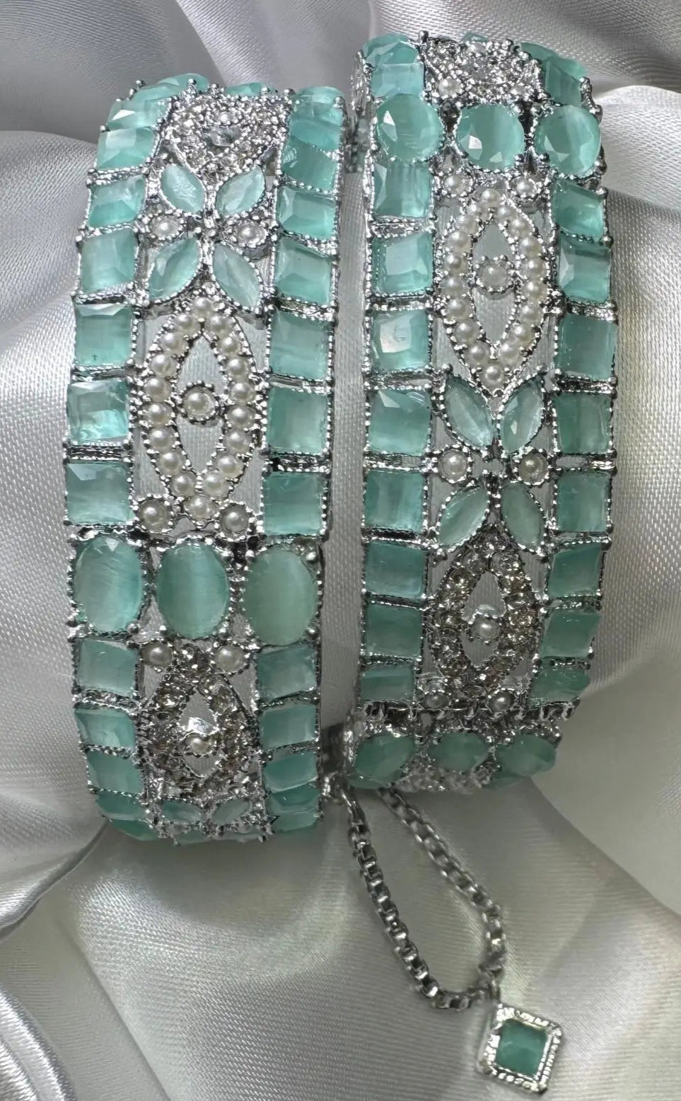 Pair of turquoise and silver openable bangles on a white satin background
