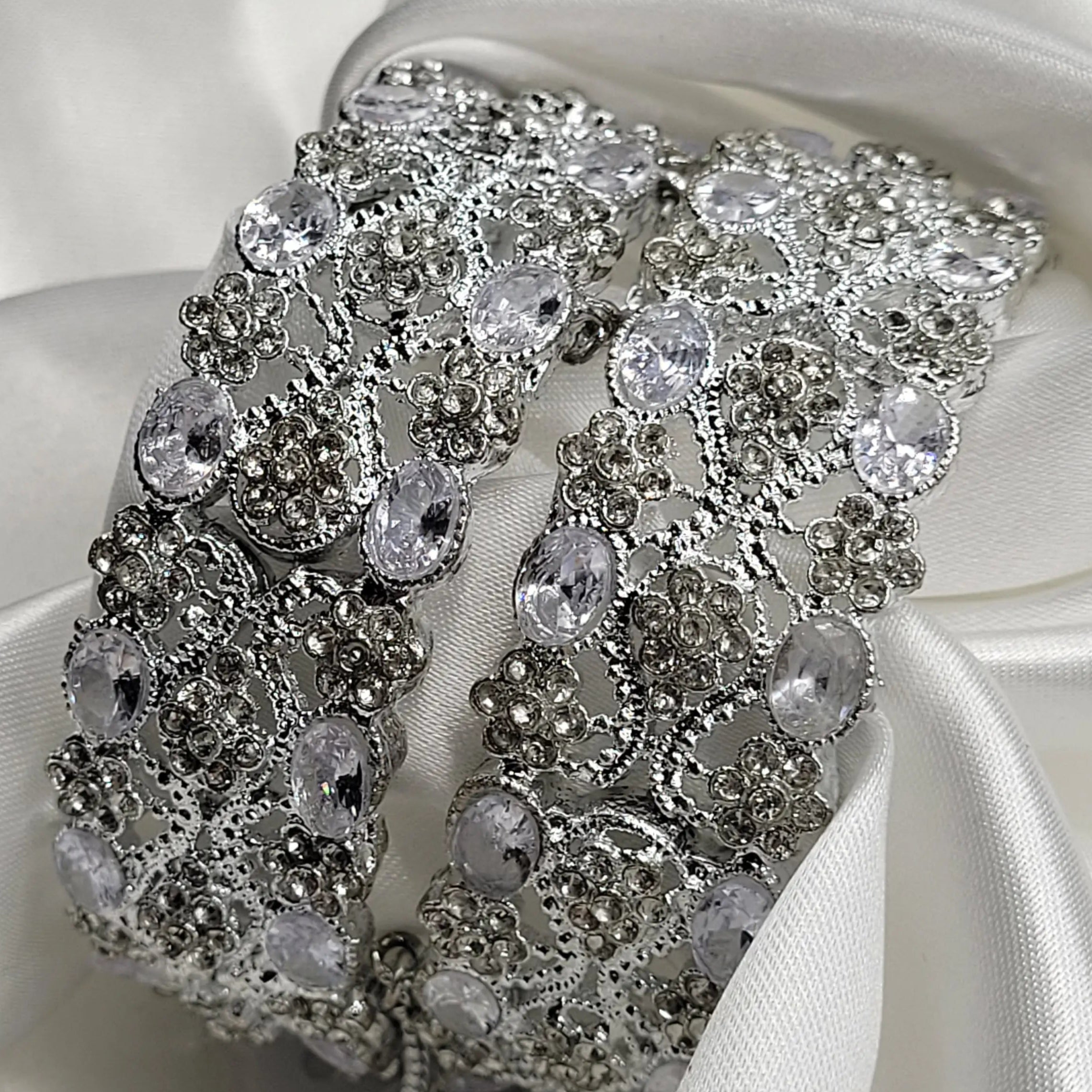 Silver bracelet with clear stones on a white satin background
