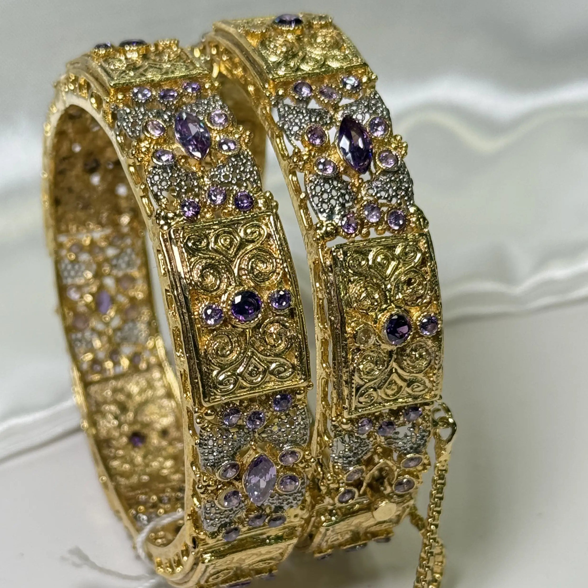 Close-up of JV3010 engraved gold bangles with marquise purple CZ crystals